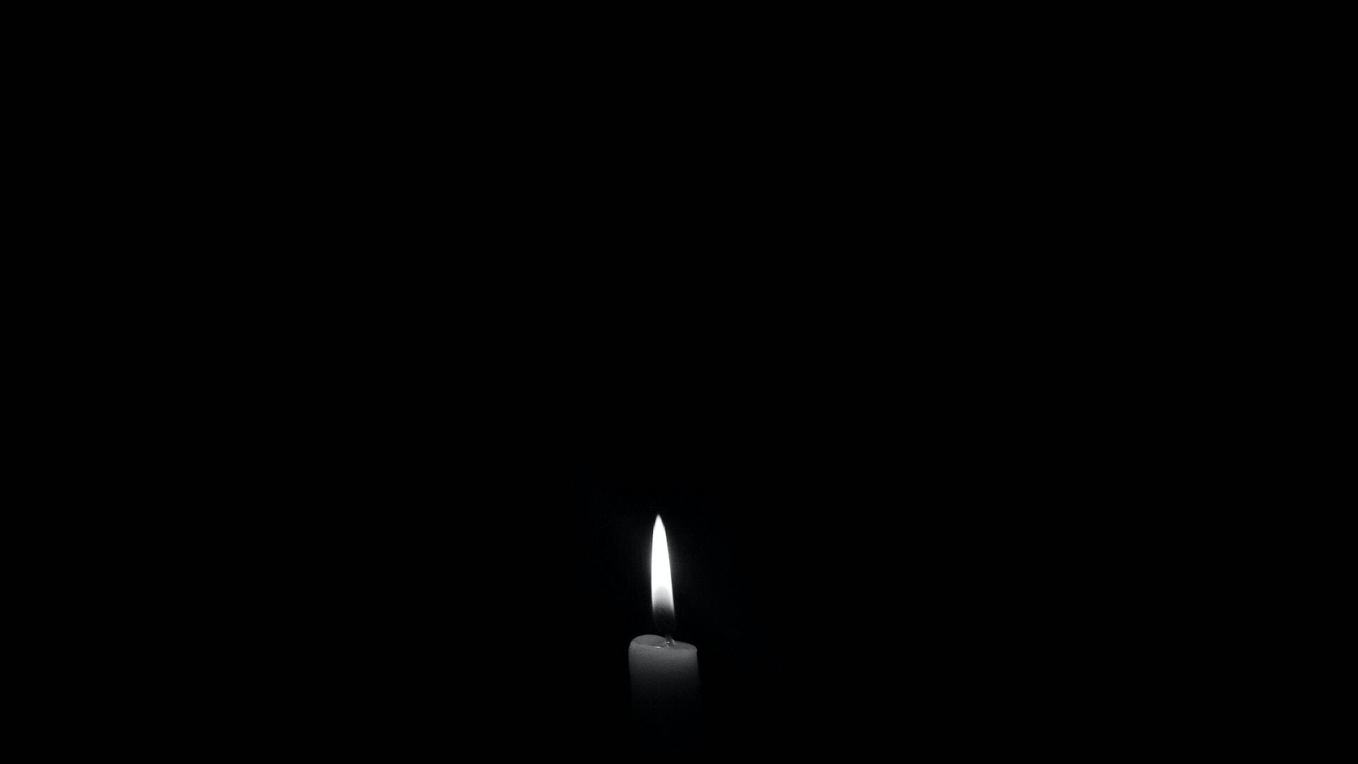 Black Desktop 桌布 壁紙 — 一支點燃的白色蠟燭在漆黑背景上散發出柔和的光芒。
