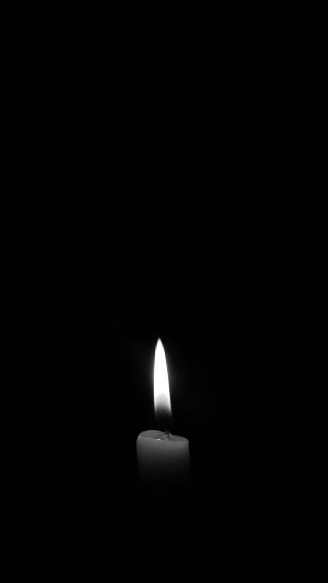 minimal dark iPhone 桌布 壁紙 — 一支點燃的蠟燭在漆黑背景上投射出柔和的光芒，構成極簡的黑白構圖。