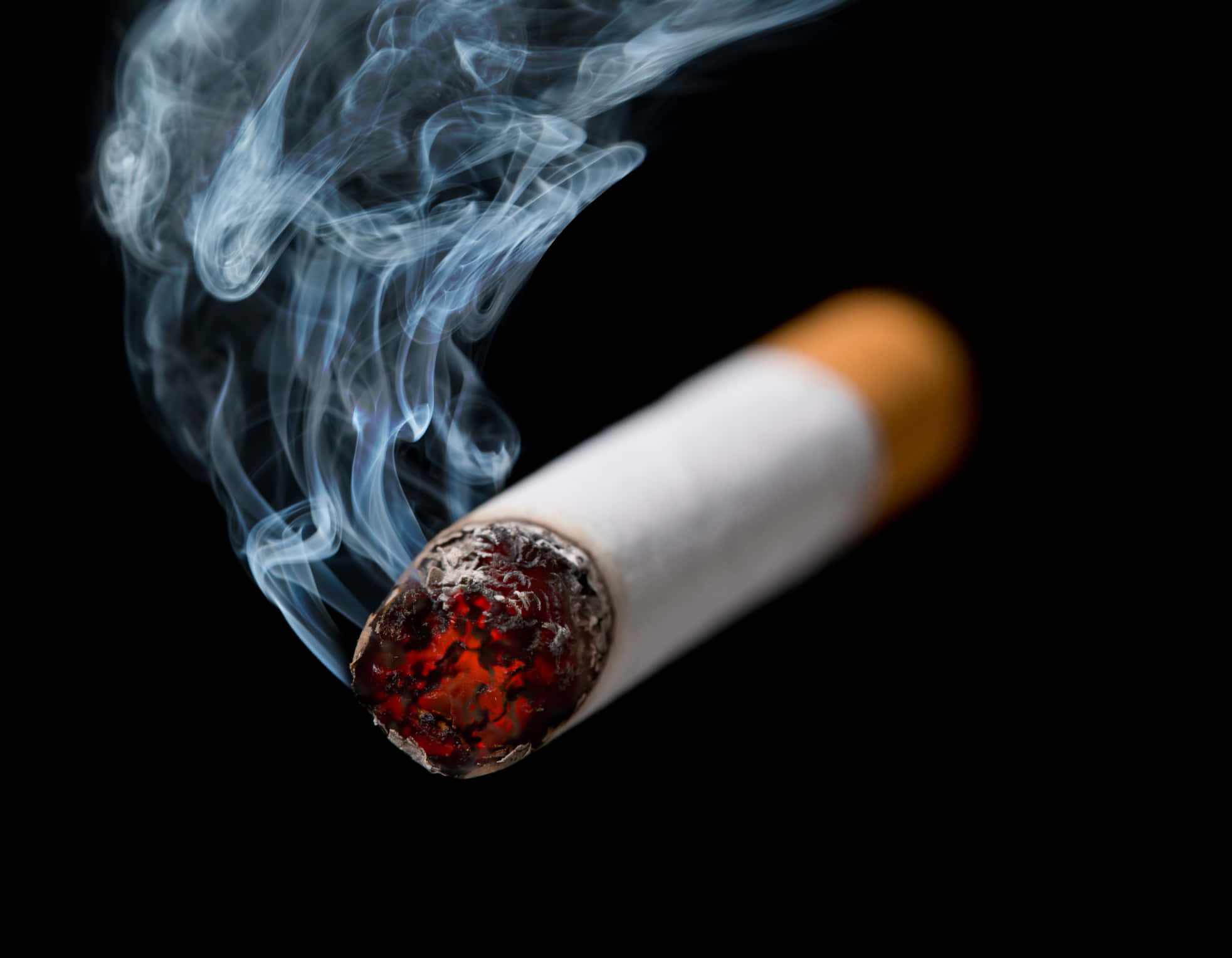 Cigarette 桌布 壁紙 — 一支點燃的香煙特寫，背景為黑色，從發光的煙頭升起旋轉的藍色煙霧。