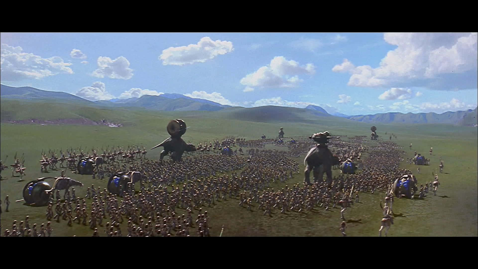 The Battle Of Naboo 桌布 壁紙 — 一支龐大的微型士兵軍隊在翠綠的平原上行進，頭頂是明亮的藍天，飄著蓬鬆的白雲，遠方有山巒。