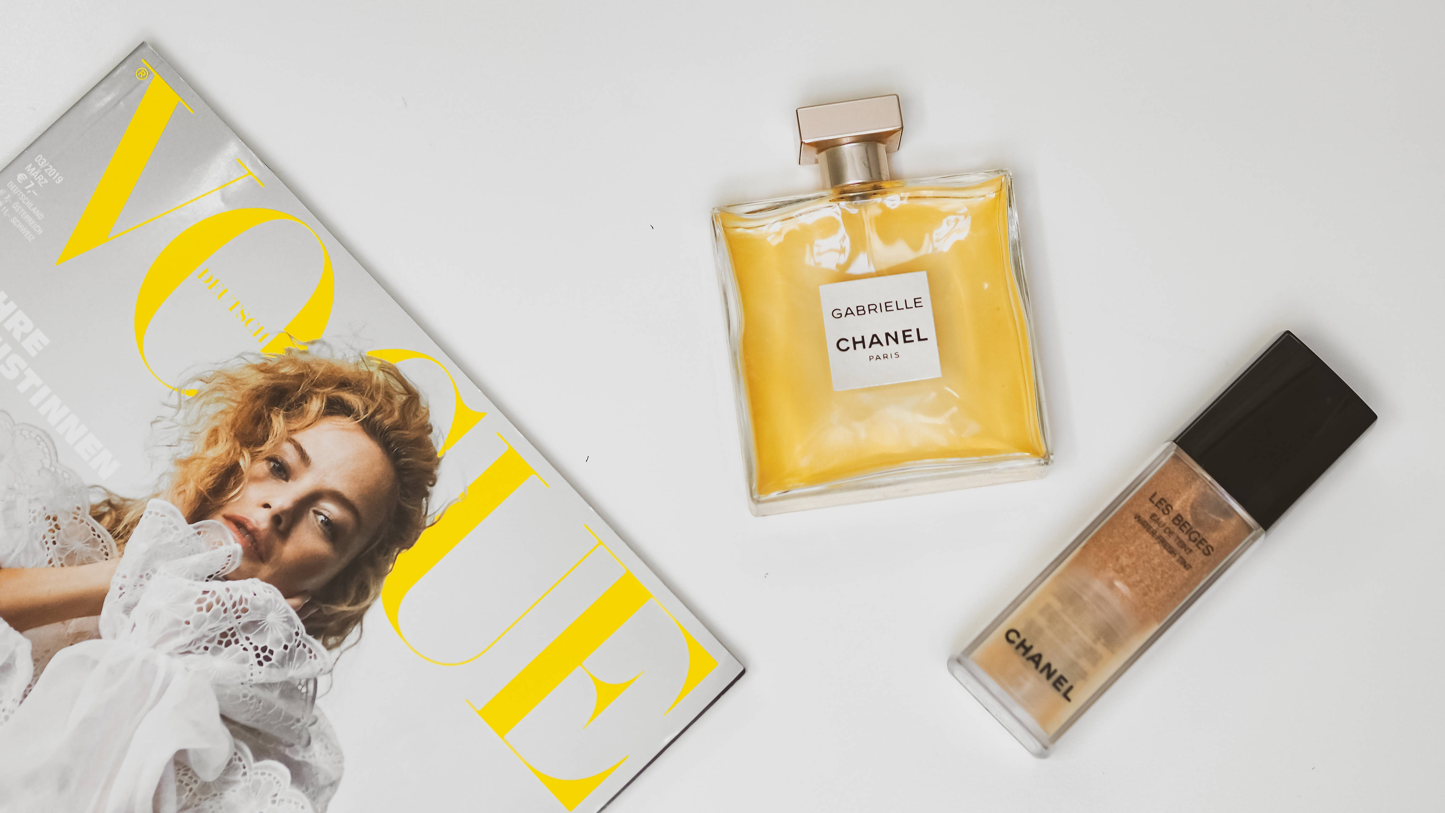 Chanel 桌布 壁紙 — 一本Vogue雜誌和兩件Chanel美容產品整齊地排列在純白色表面上。