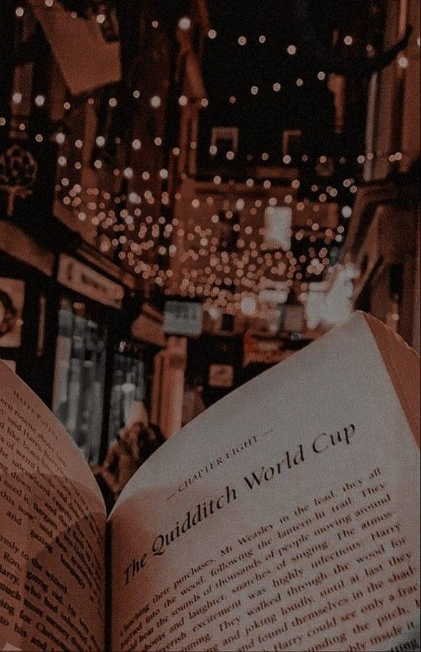 在昏暗街道上，發光的串燈下，一本名為Quidditch World Cup的打開的書。