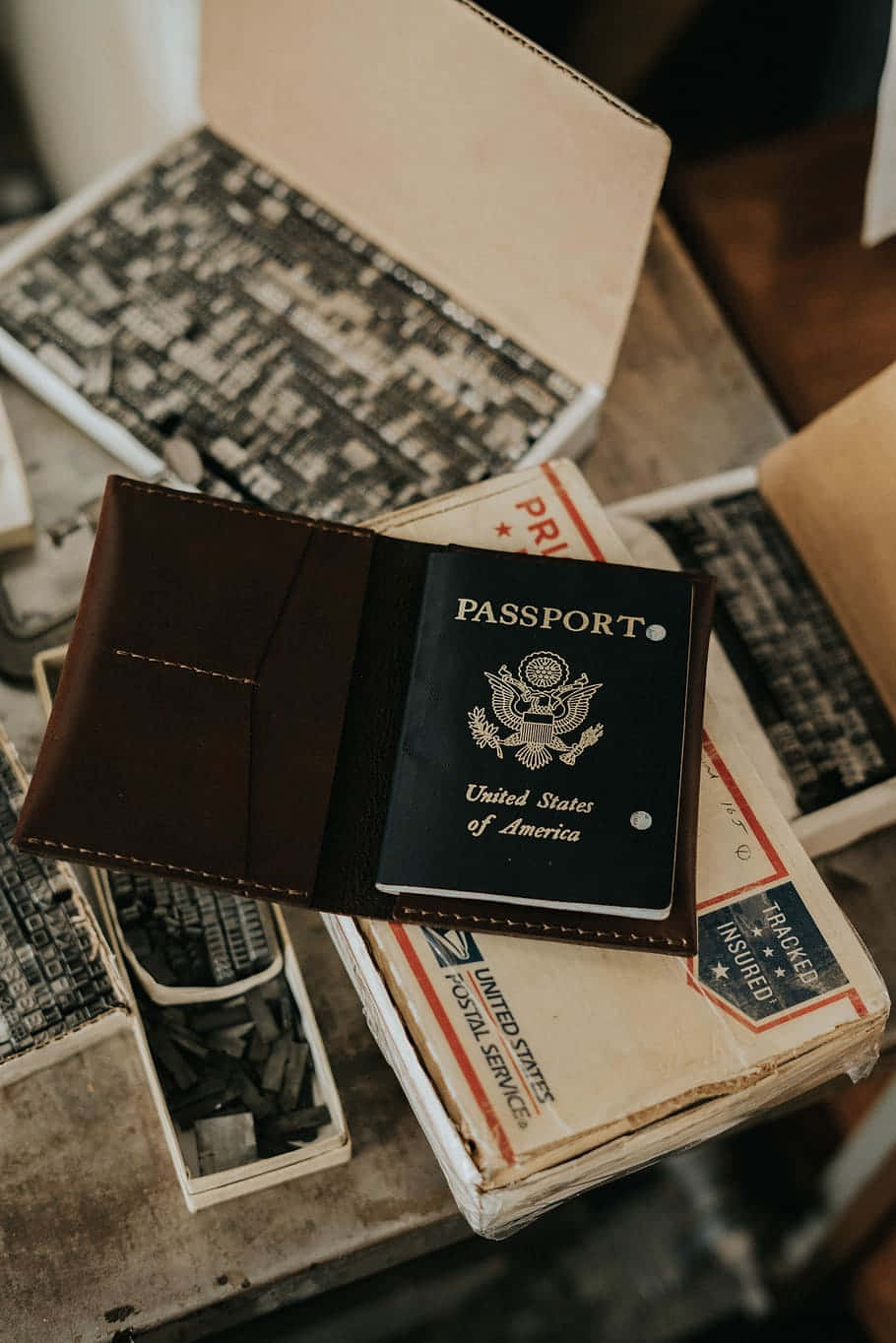 Passport 桌布 壁紙 — 一本復古美國護照打開放在棕色皮套內，置於舊郵箱和字體塊之上。
