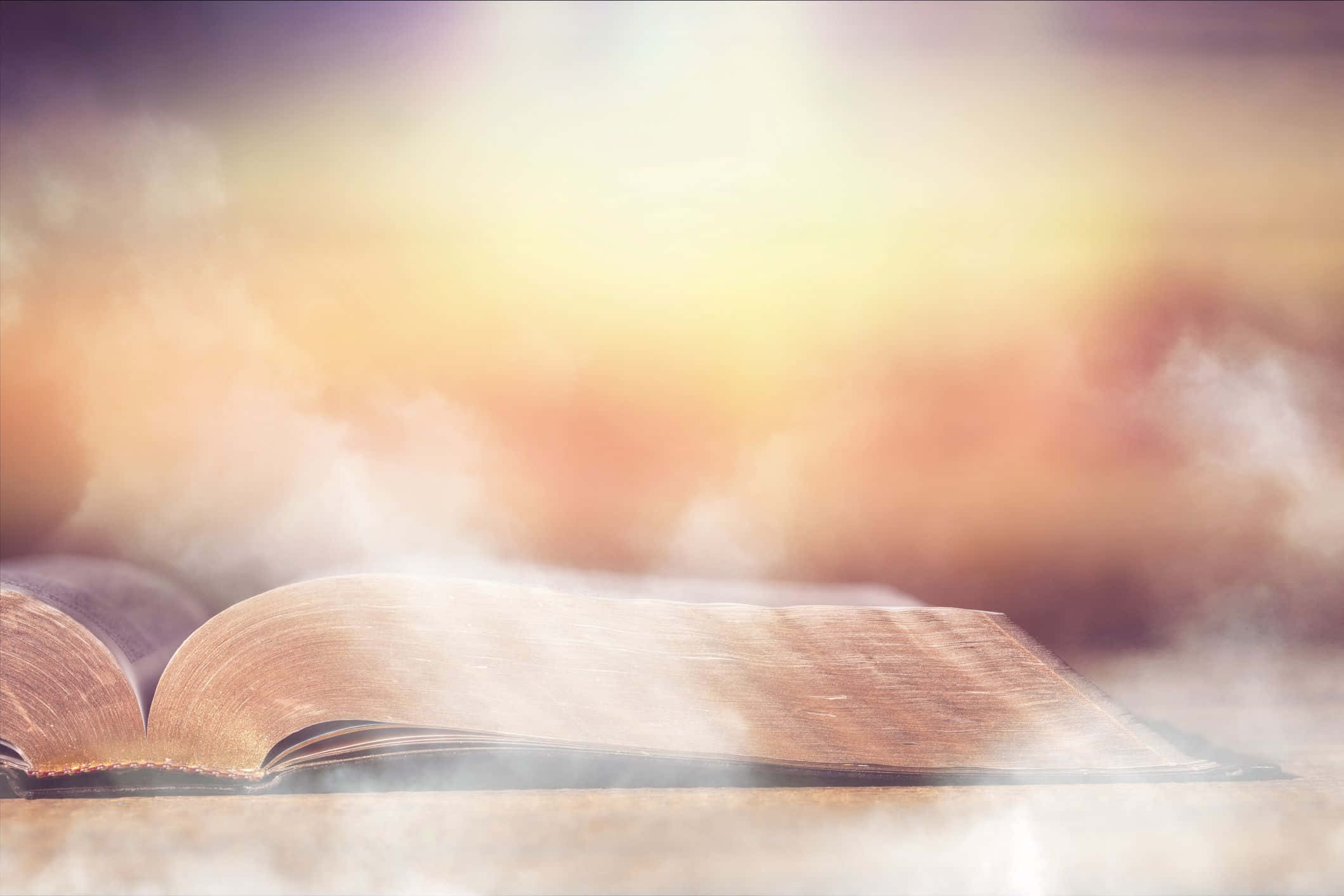 Kingdom Of God 桌布 壁紙 — 一本打開的古書放在表面上，背景有柔和的金色光芒和朦朧的散景。