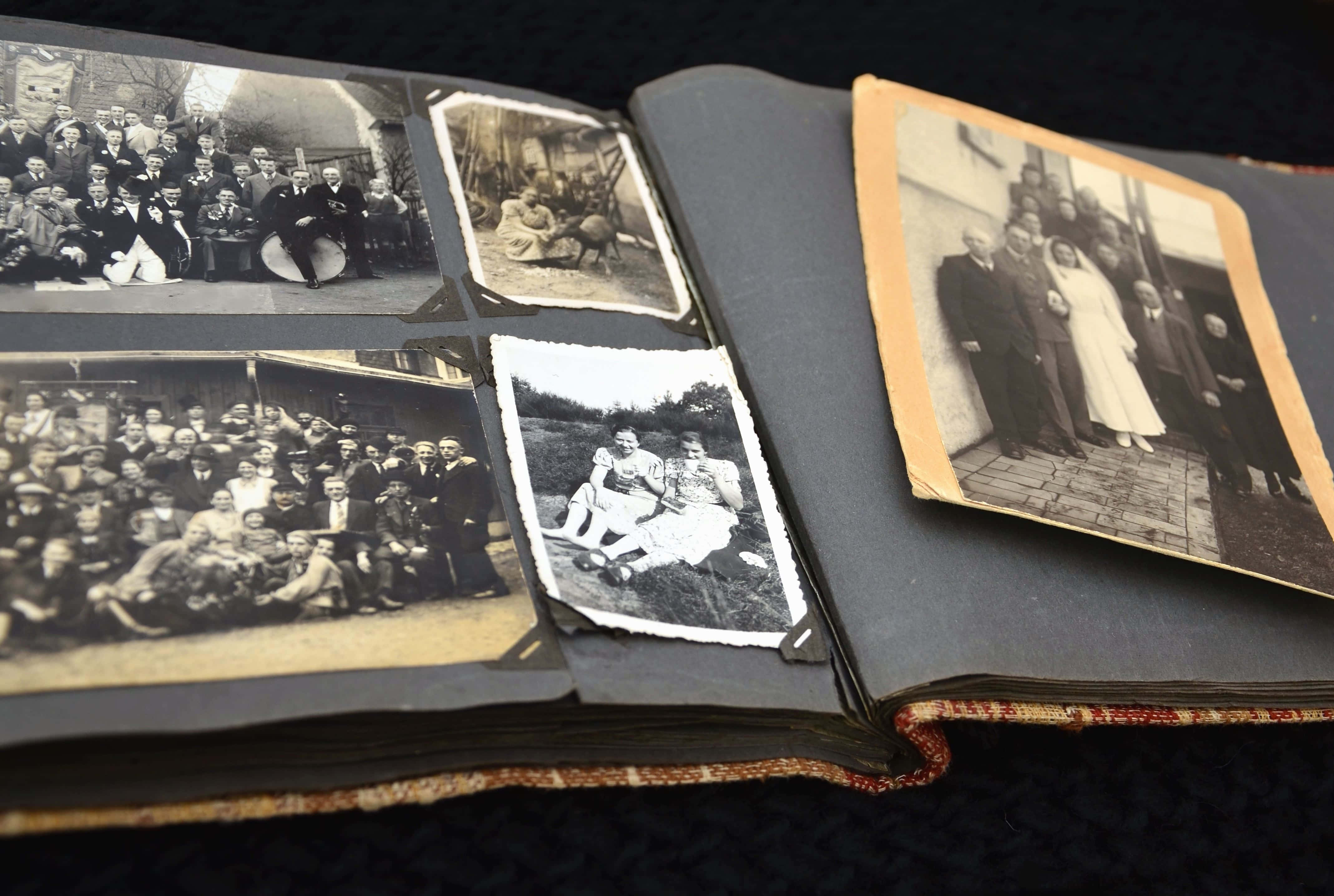 album 桌布 壁紙 — 一本打開的復古相簿在帶有紋理的頁面上展示著棕褐色調和黑白的家庭肖像。