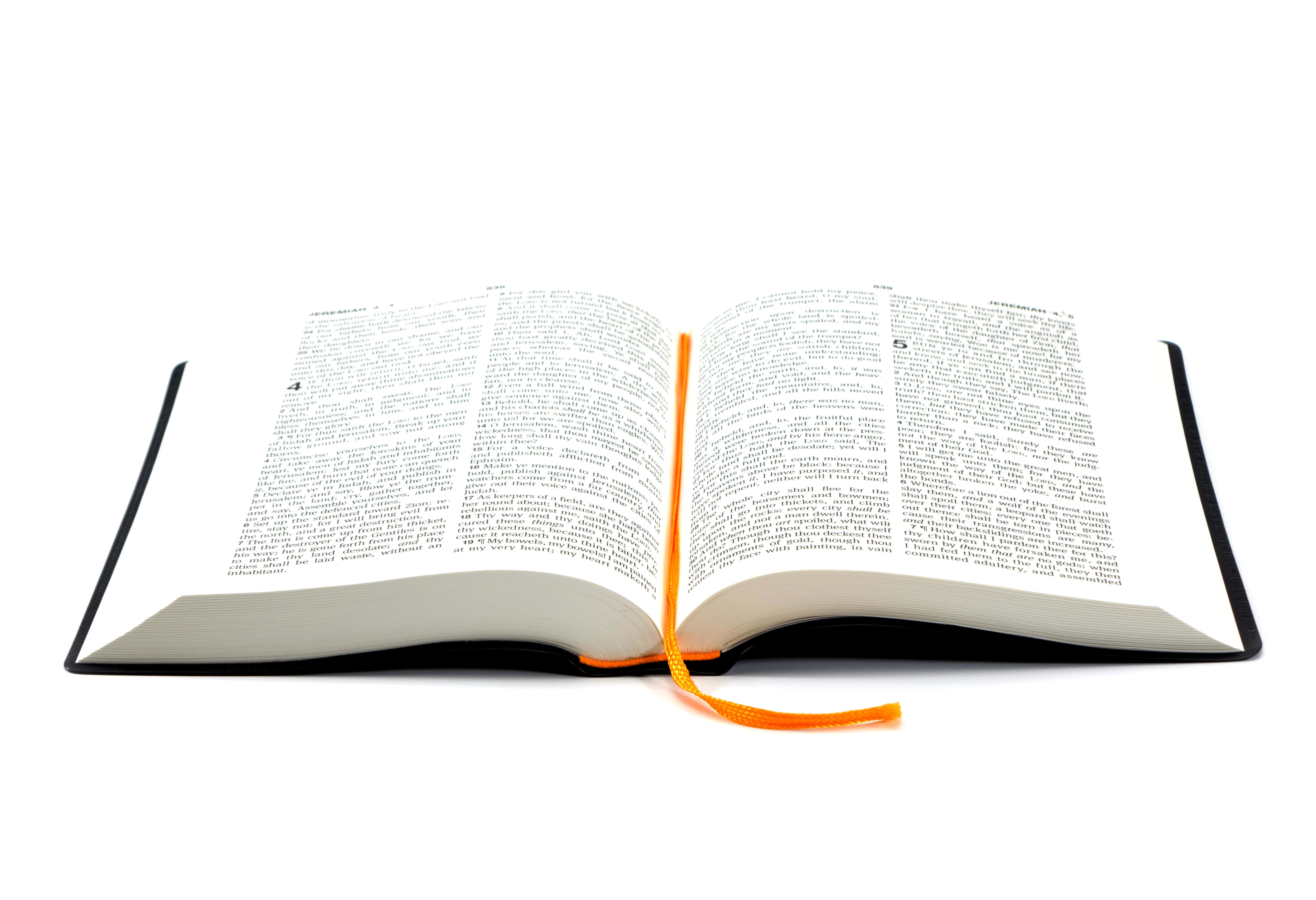 Biblical 桌布 壁紙 — 一本打開的書，泛黃的舊頁面上顯示密集的黑色文字和紅色章節標題，在溫暖的燈光下。