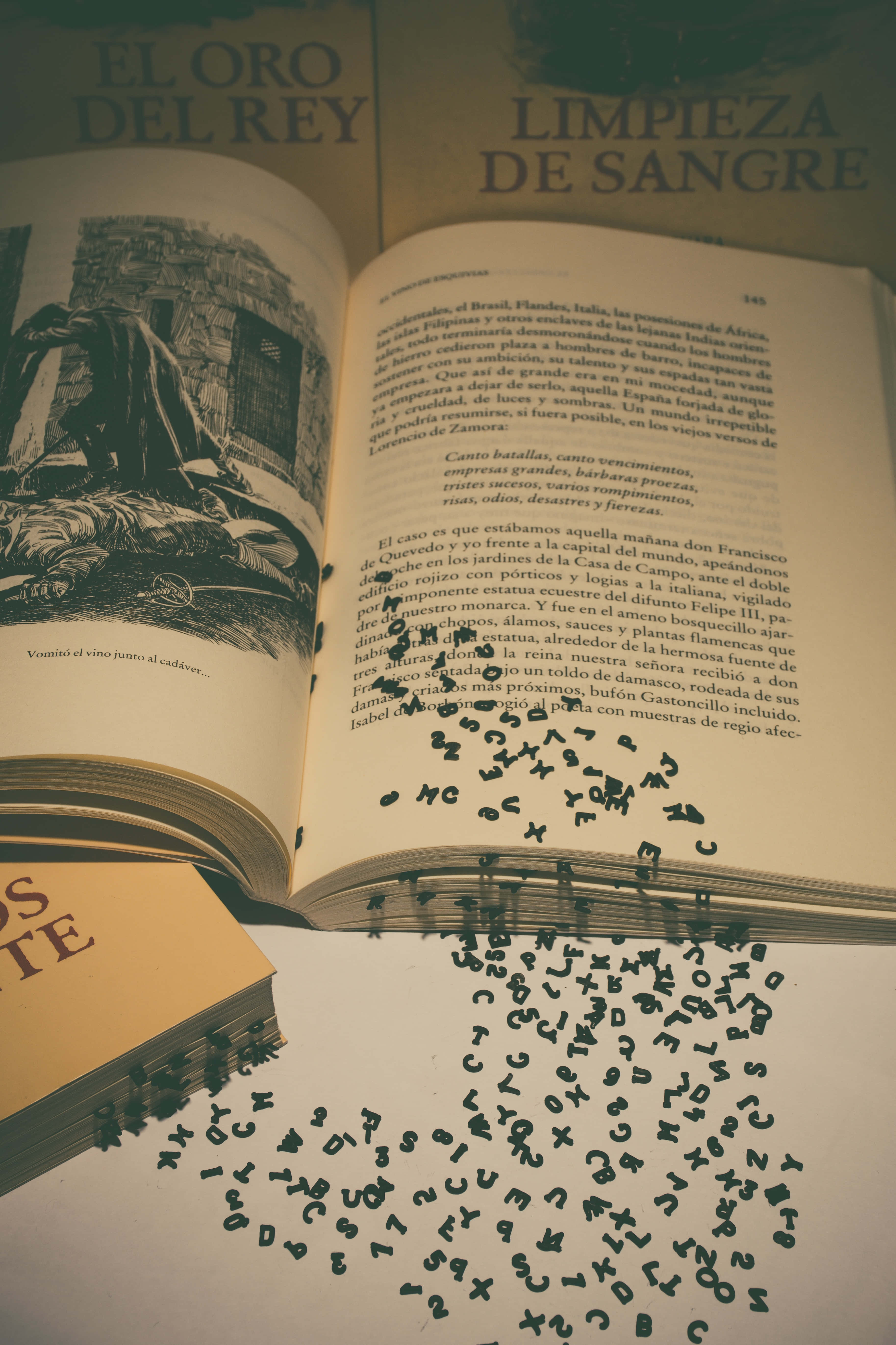 literature 桌布 壁紙 — 一本打開的書，白色表面上散落著黑色字母，旁邊是一本帶有金色字母的合上的書。