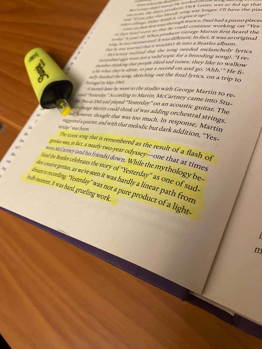 Highlight 桌布 壁紙 — 一本打開的書的特寫，書頁上有黃色螢光筆標記，並有一支綠色螢光筆擱在頁面上。