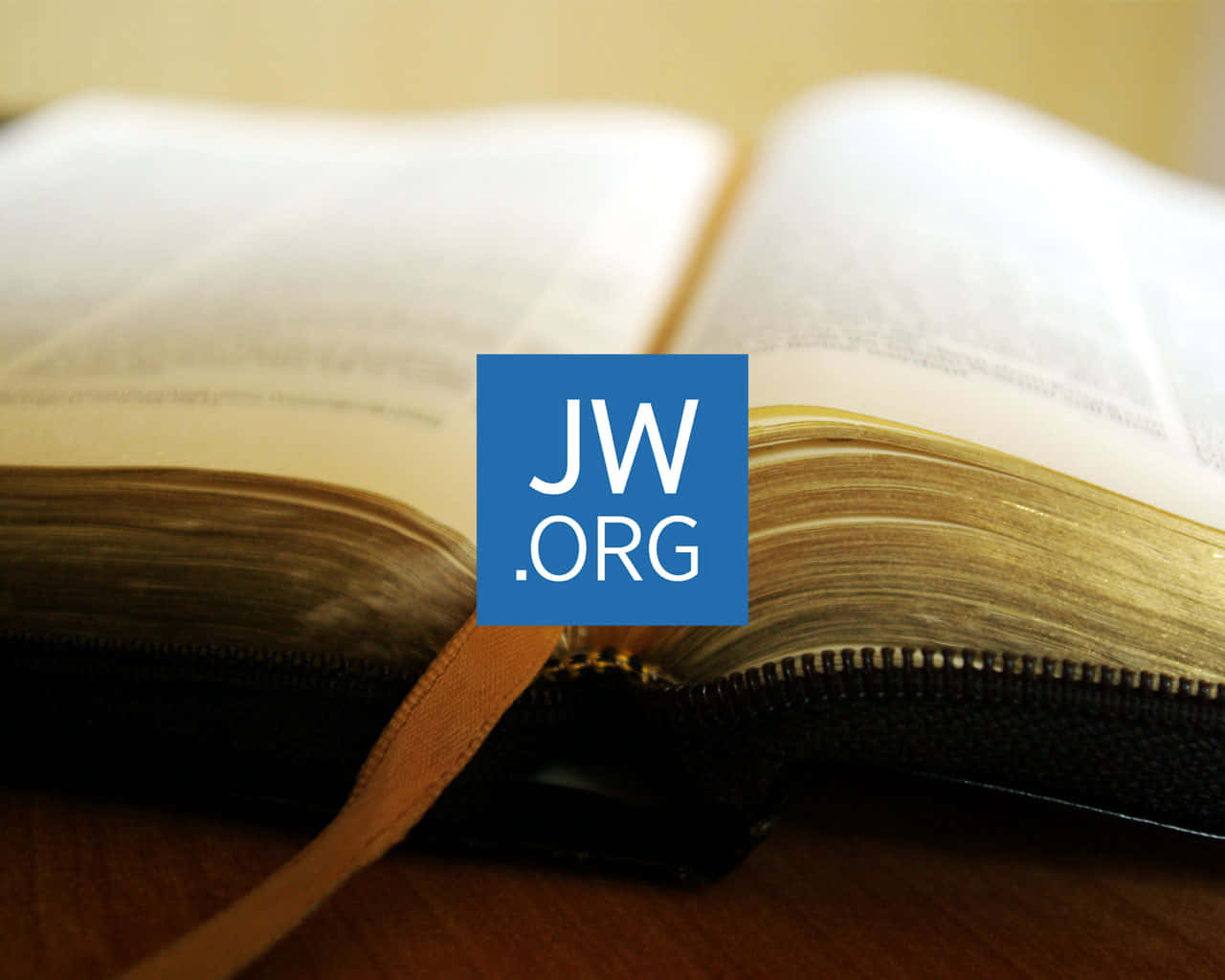 聖經 桌布 壁紙 — 一本打開的書的特寫，書頁上疊加了一個藍色的JW.ORG標誌。