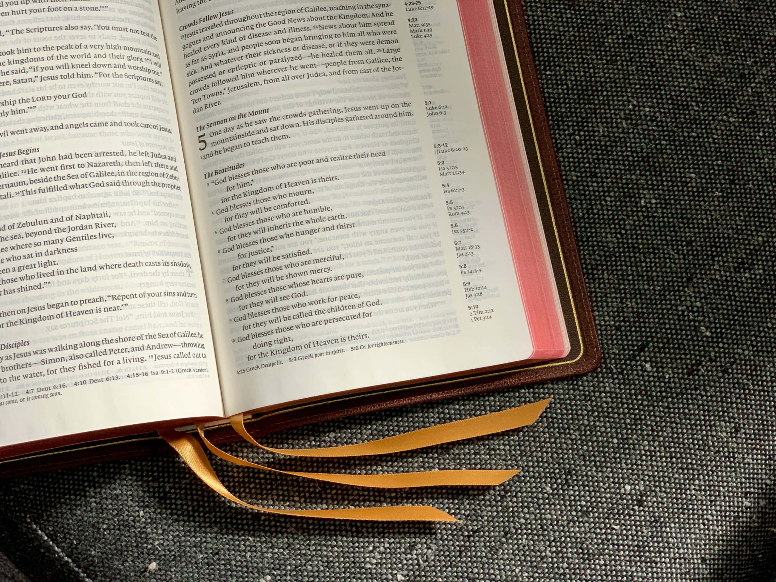 Scripture 桌布 壁紙 — 一本打開的聖經，紅白頁面，放在有紋理的灰色表面上，顯示經文和章節參考。