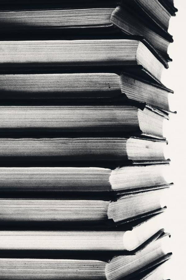 Education 桌布 壁紙 — 一本本堆疊的書籍，書脊和書頁帶有紋理，在明亮的背景下形成節奏線條，呈現鮮明的黑白特寫。