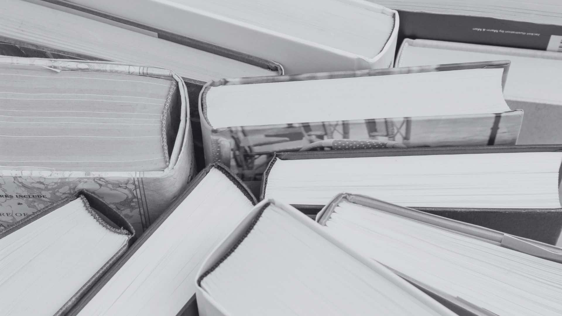 Black And White Book 桌布 壁紙 — 一本本疊起的書本特寫，採用單色調，書脊和書頁邊緣清晰可見，營造出富有質感的學術構圖。