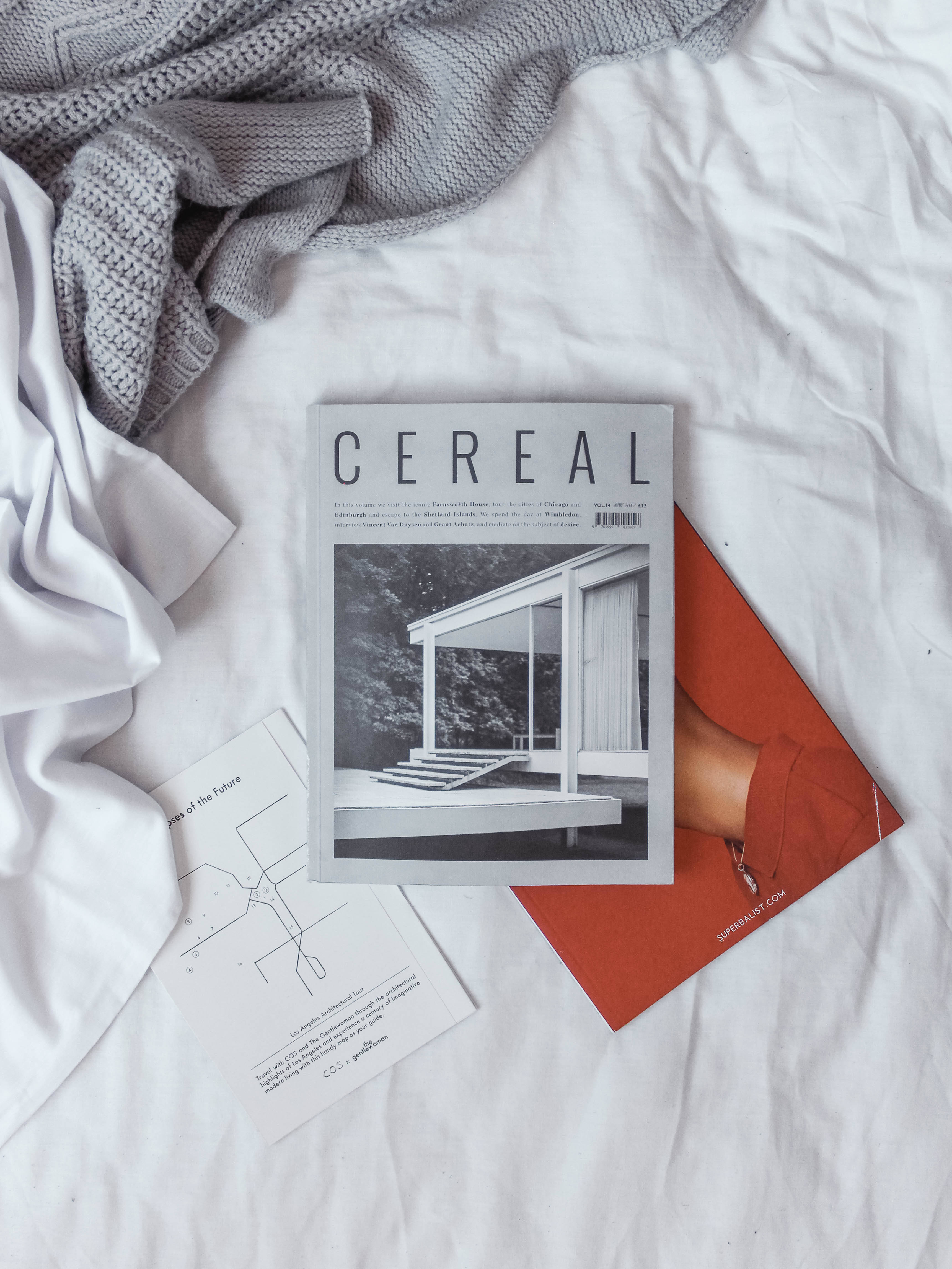 Magazine 桌布 壁紙 — 一本極簡雜誌《CEREAL》放在白色床單上，旁邊有一條灰色針織毯和一個紅色信封。