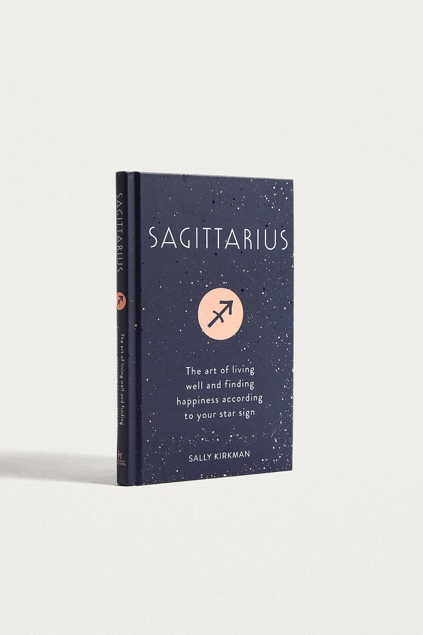 sagittarius 桌布 壁紙 — 一本海軍藍色的書，書名為 Sagittarius，帶有星光封面和橙色箭頭符號，直立於純白色背景前。