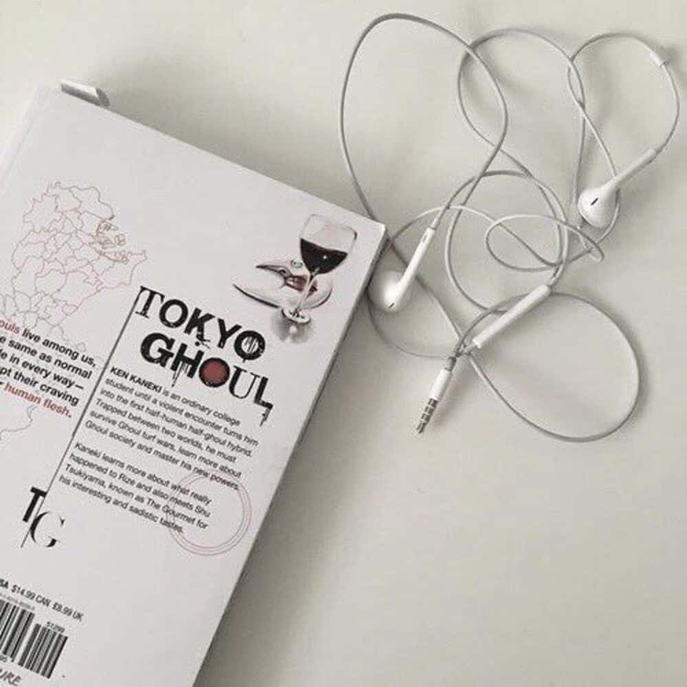 桌布 壁紙 — 一本白色的東京喰種書本，旁邊放著纏繞的白色耳機，在純淺灰色表面上。