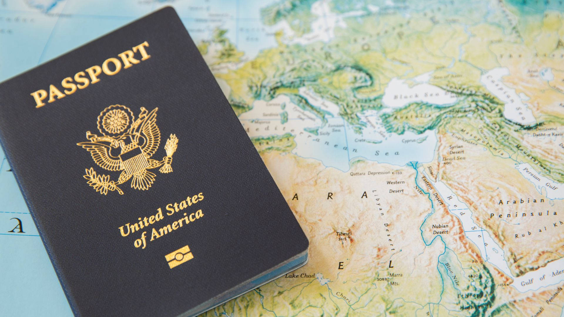 Passport 桌布 壁紙 — 一本美國護照放在一張突出顯示中東及周邊地區的詳細地圖上。