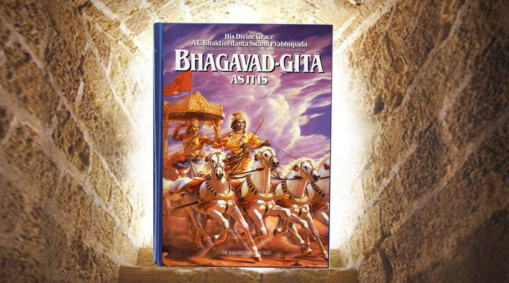 Indian 桌布 壁紙 — 一本色彩鮮豔的插圖版《薄伽梵歌》書籍，靜置於沐浴在溫暖光線中的石階上。