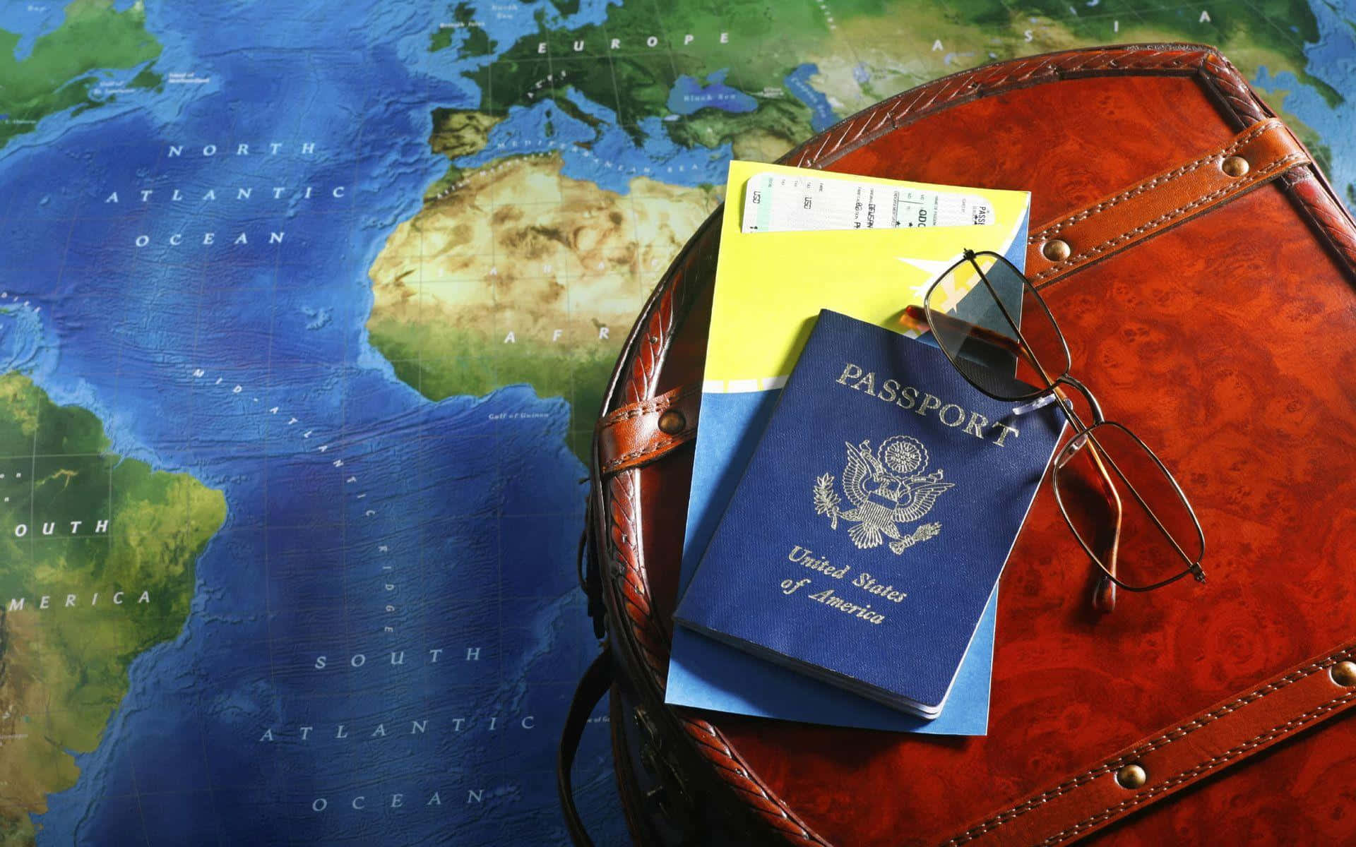 Passport 桌布 壁紙 — 一本藍色美國護照和黃色登機證放在一個復古皮革行李箱上，行李箱置於顯示歐洲、非洲和海洋的世界地圖上。