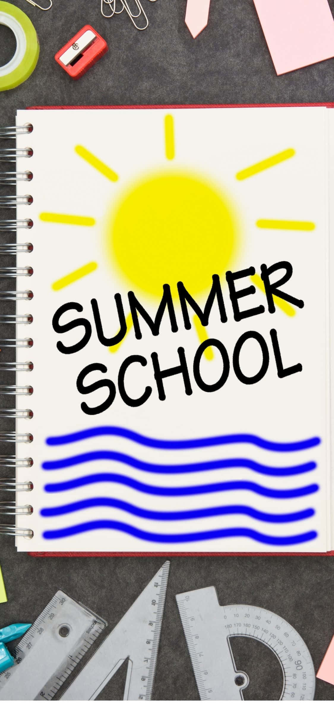 夏天 iPhone 桌布 壁紙 — 一本螺旋筆記本，上面有「SUMMER SCHOOL」字樣和黃色太陽圖案，放在被學校用品包圍的書桌上。