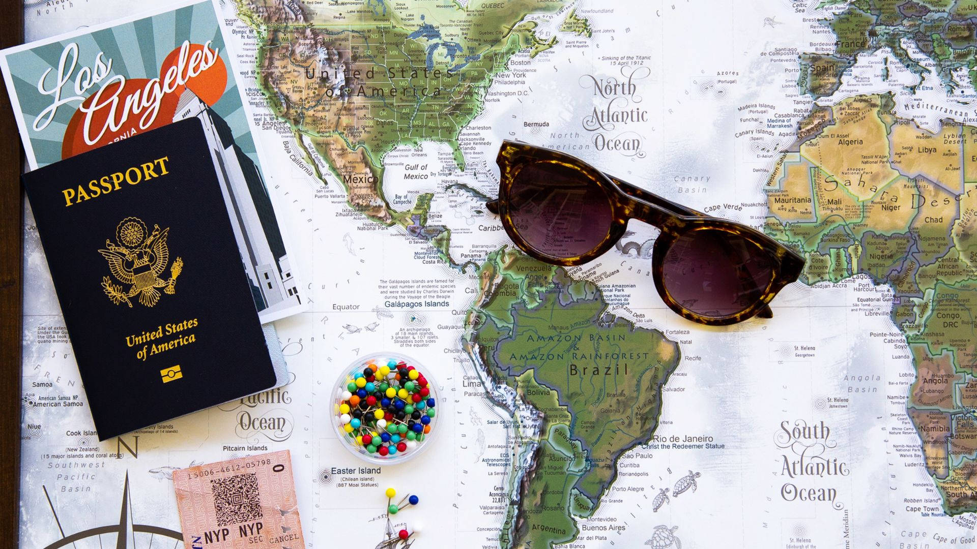 Sunglasses 桌布 壁紙 — 一本護照、太陽眼鏡和旅行票據放在一張復古世界地圖上，突顯全球冒險。