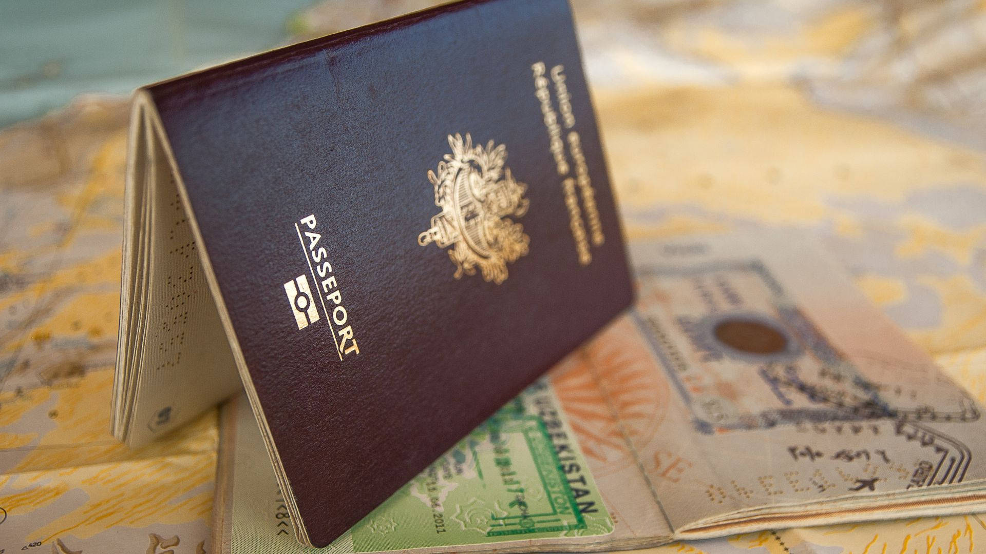 Passport 桌布 壁紙 — 一本酒紅色的歐洲護照放在世界地圖上散開的外幣和旅行文件上。