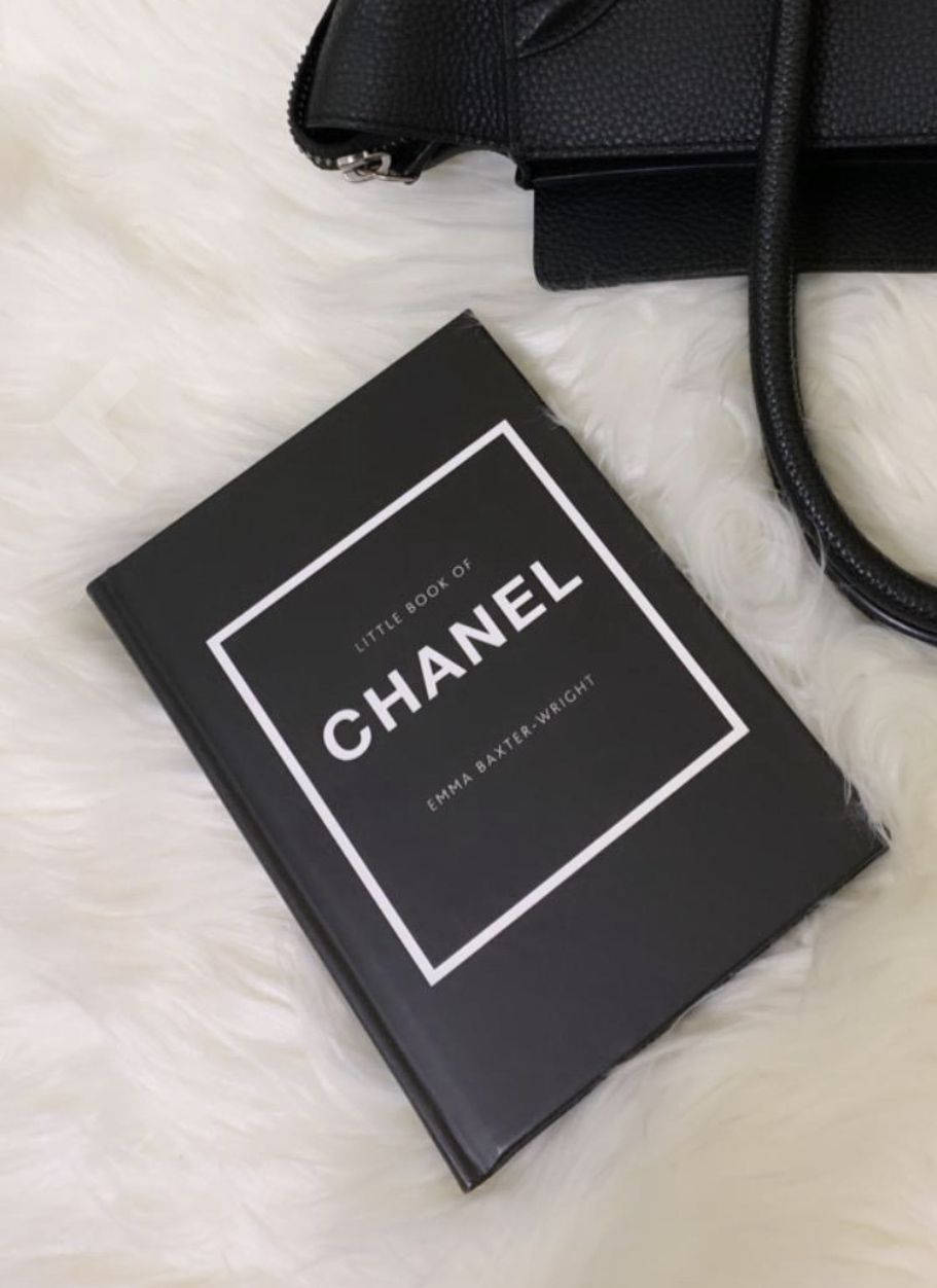 Chanel Aesthetic 桌布 壁紙 — 一本黑色 Chanel 書本和相配的手袋優雅地放在柔軟的白色毛絨表面上。
