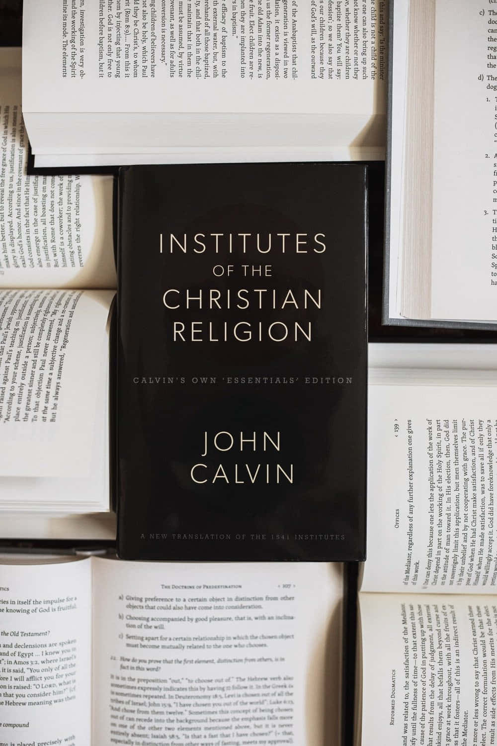 Theology 桌布 壁紙 — 一本黑色精裝書，名為《基督教要義》，作者約翰·加爾文，放在一本神學文本的打開頁面上。