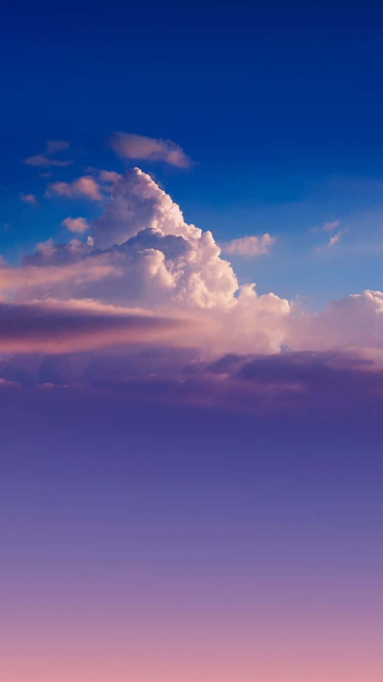 Blue Sky Aesthetic 桌布 壁紙 — 一朵雄偉的積雲在深藍色的暮色天空中散發出粉紅色和紫色的光芒。