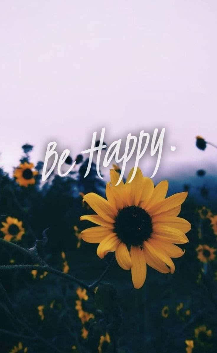 Be Happy 桌布 壁紙 — 一朵鮮豔的向日葵在柔和的紫色天空下盛開，中央優雅地寫著鼓舞人心的短語 be happy。