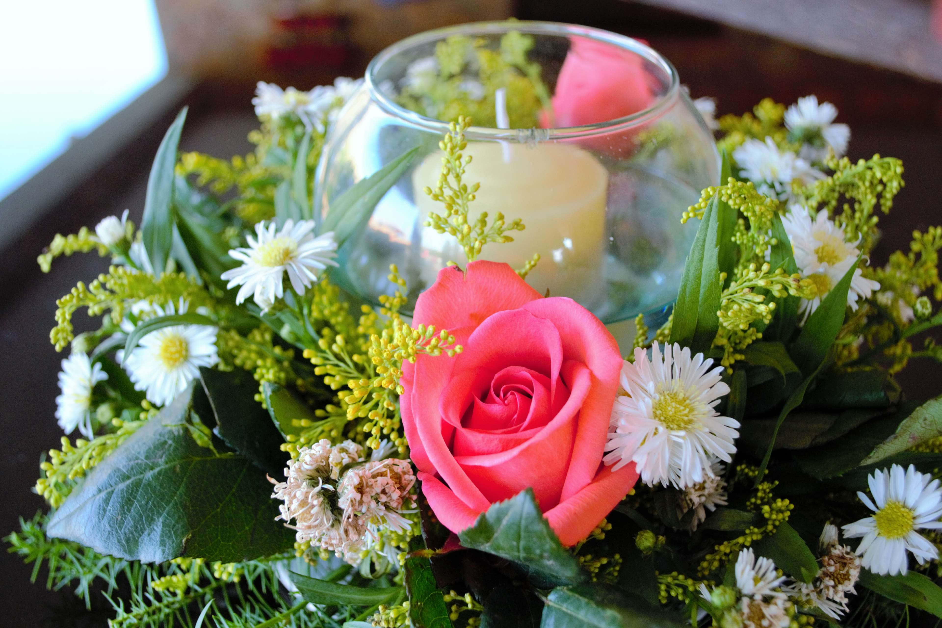 Wedding Flowers 桌布 壁紙 — 一朵鮮豔的粉紅玫瑰和白色雛菊圍繞著深色木質表面上的玻璃燭台。
