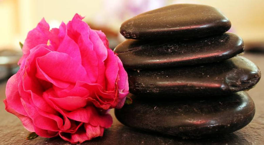 Meditation 桌布 壁紙 — 一朵鮮豔的粉紅玫瑰在木質表面上，旁邊是一堆光滑的深色石頭，正在盛開。