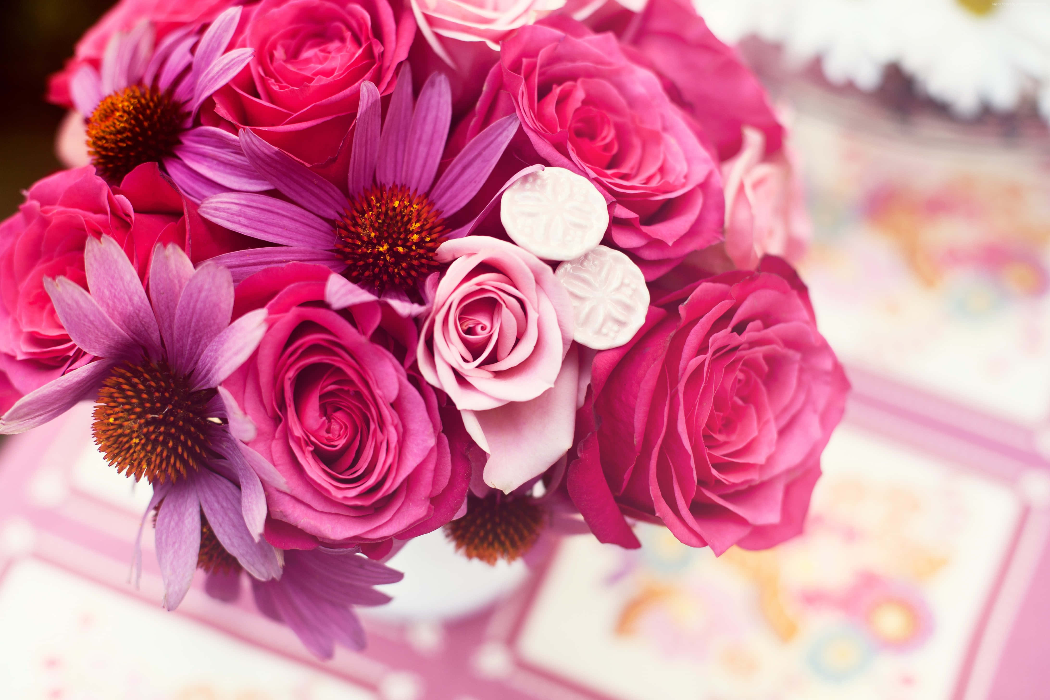 Bouquet 桌布 壁紙 — 一束充滿活力的粉紅玫瑰和紫色紫錐花，搭配白色裝飾元素，放置在粉彩圖案表面上。