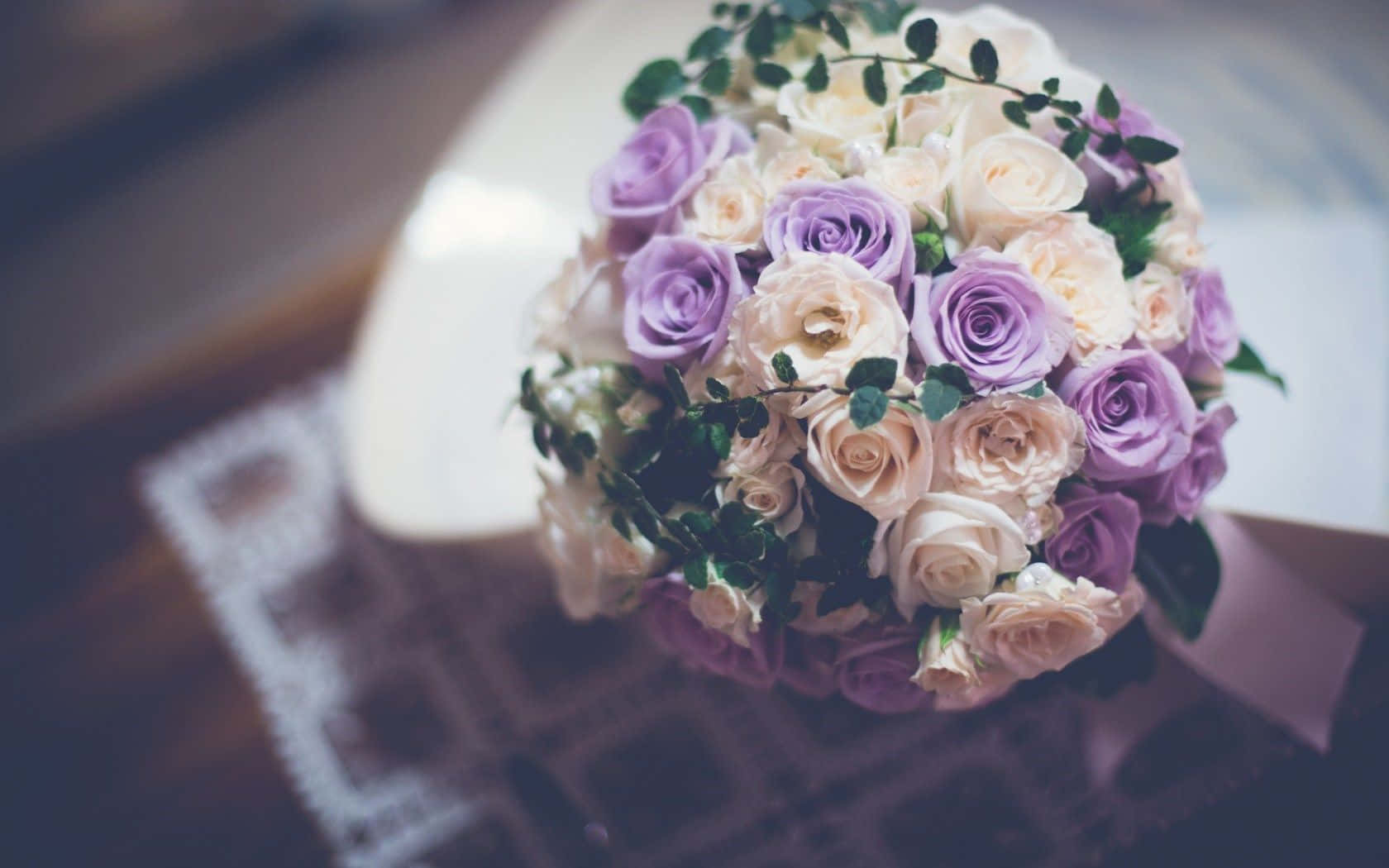 Wedding Flowers 桌布 壁紙 — 一束柔焦的薰衣草和奶油色玫瑰配綠葉，放在蕾絲邊飾的表面上。