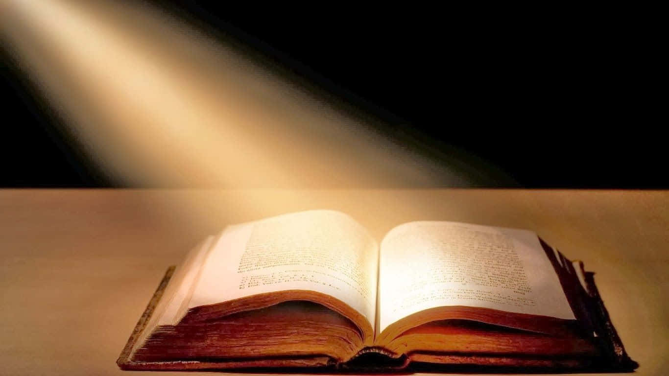Bible Study 桌布 壁紙 — 一束溫暖的光線照亮了一本放在木質表面上、背景深色的打開的書。