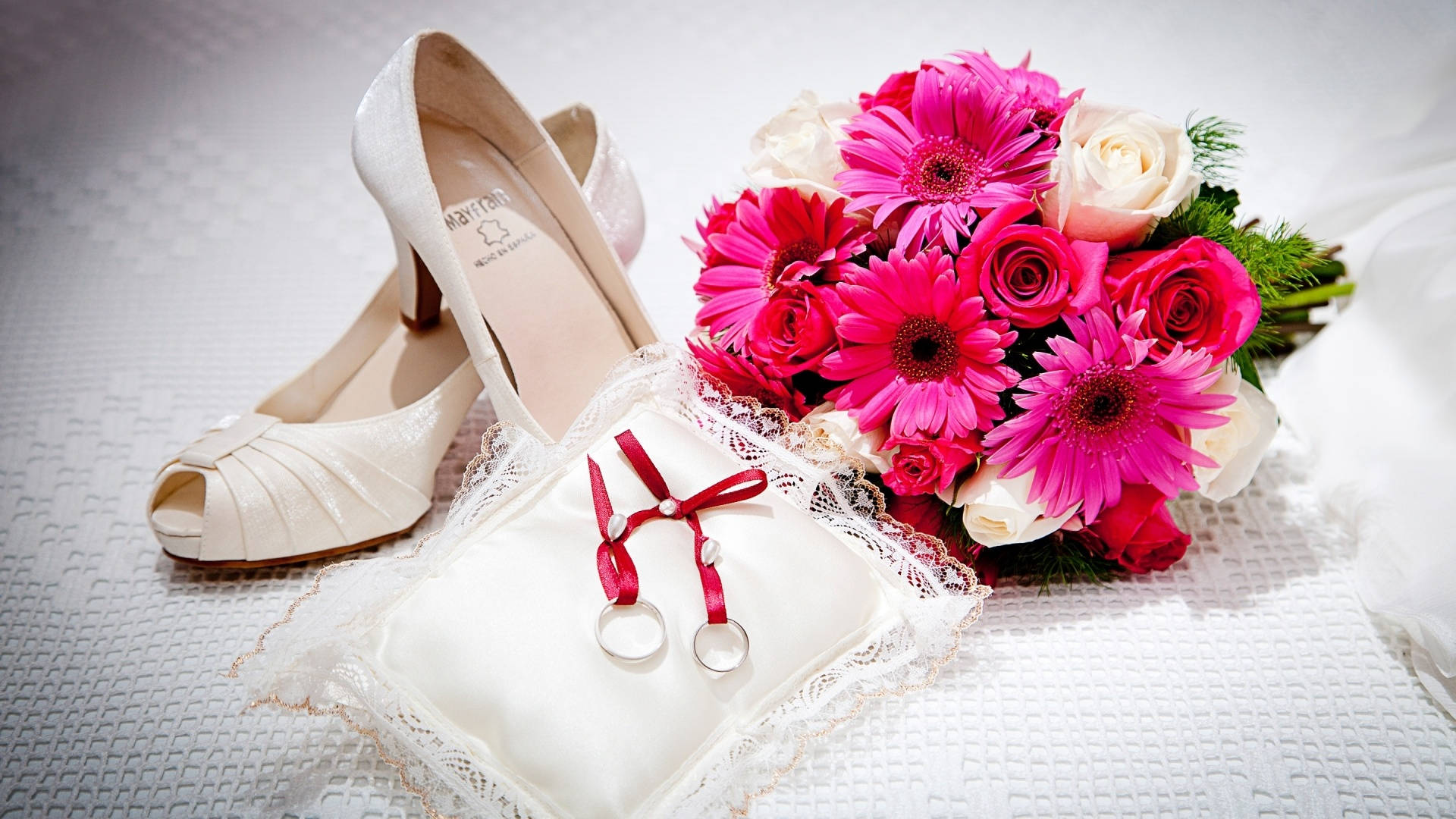 Wedding 桌布 壁紙 — 一束粉白色新娘花束放在象牙色婚鞋和一個帶有兩條銀色帶的戒指枕旁。