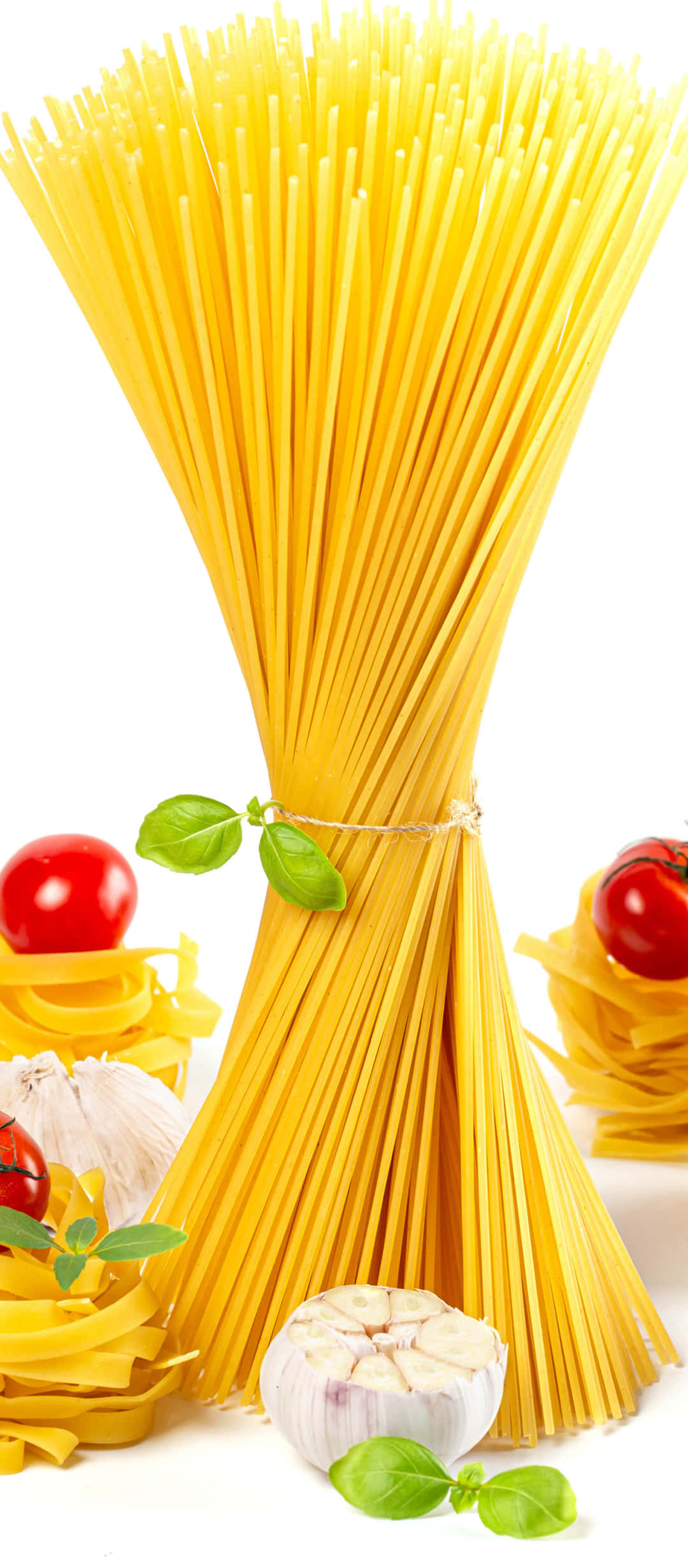 Best Pasta 桌布 壁紙 — 一束色彩鮮豔的生義大利麵用繩子綁著，周圍是新鮮番茄、羅勒和大蒜，背景是潔淨的白色。