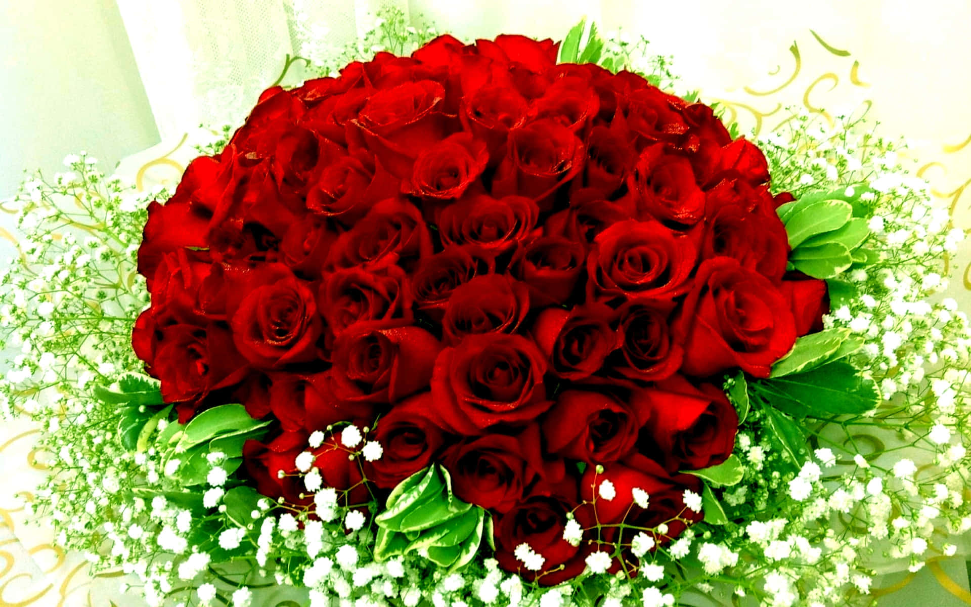 Flowers 桌布 壁紙 — 一束茂盛的鮮紅玫瑰，周圍環繞著精緻的白色滿天星和綠葉，襯以柔和的金色背景。