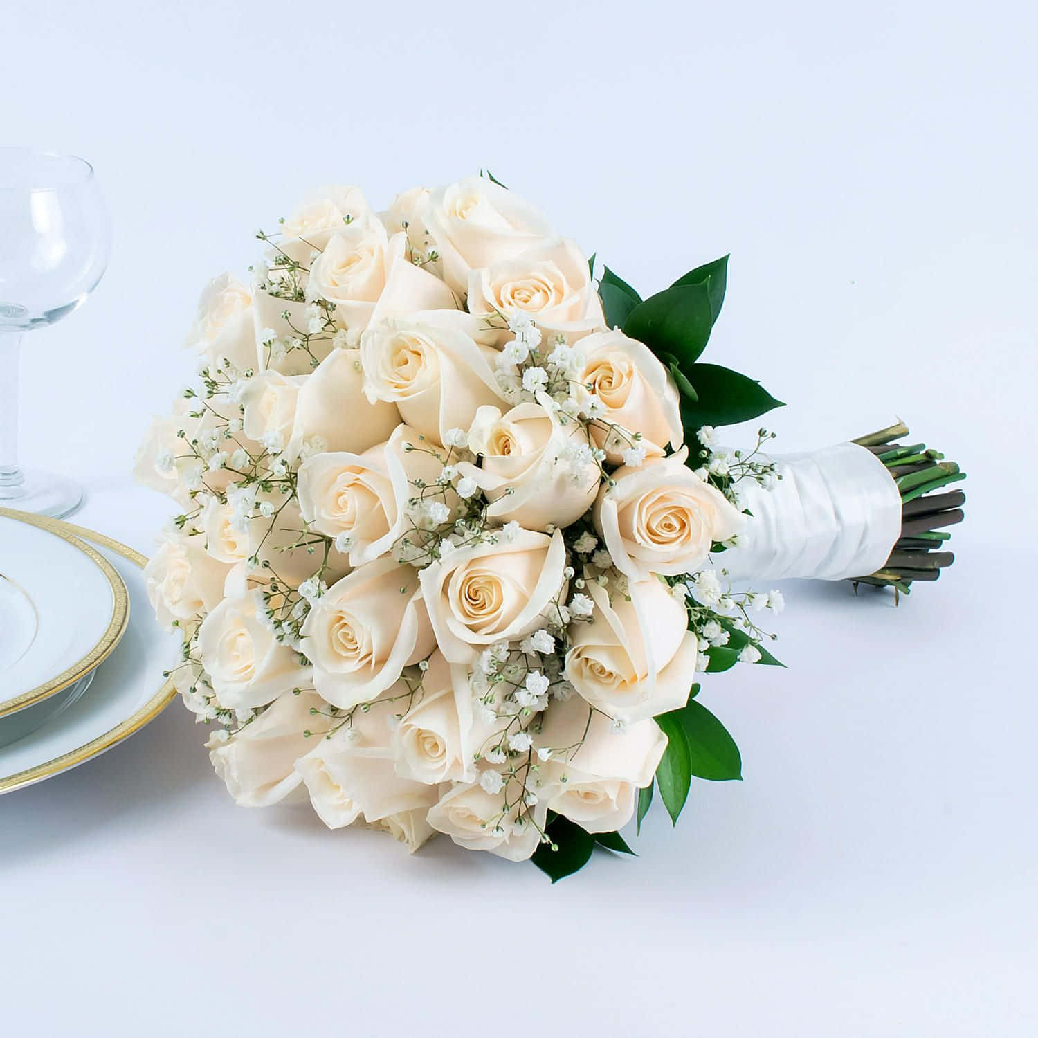 Roses Wedding 桌布 壁紙 — 一束豐盛的奶油白玫瑰和滿天星，用白色緞帶優雅包裹，旁邊放著一個酒杯和一個金邊盤子。