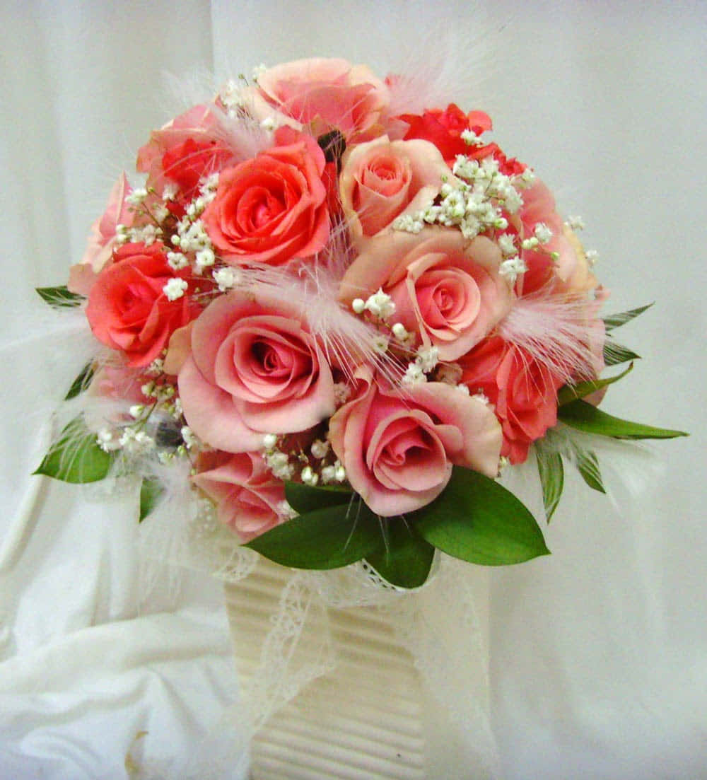 Flower Bouquet 桌布 壁紙 — 一束豐盛的珊瑚色和蜜桃色玫瑰，點綴滿天星和柔軟的粉紅色羽毛，放在一個蕾絲包裹的奶油色花瓶中。
