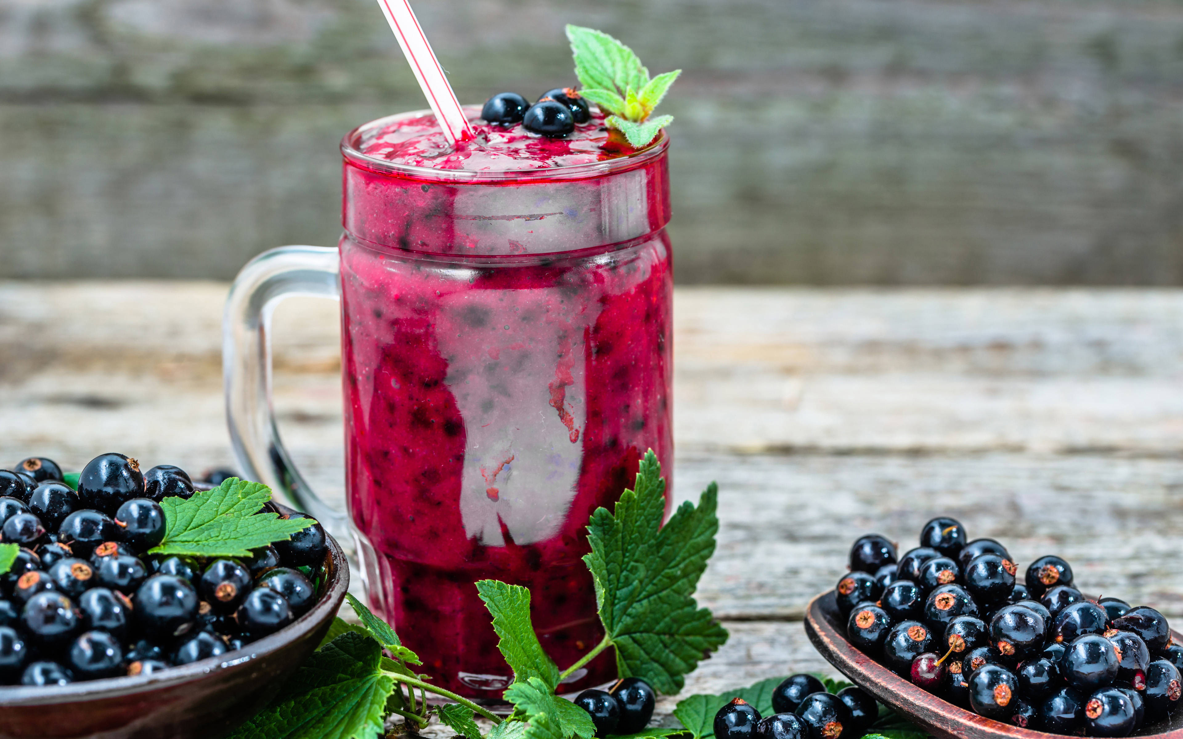 Smoothie 桌布 壁紙 — 一杯充滿活力的紅加侖子冰沙，盛在玻璃杯中，飾以新鮮漿果和薄荷，置於質樸的木桌上。