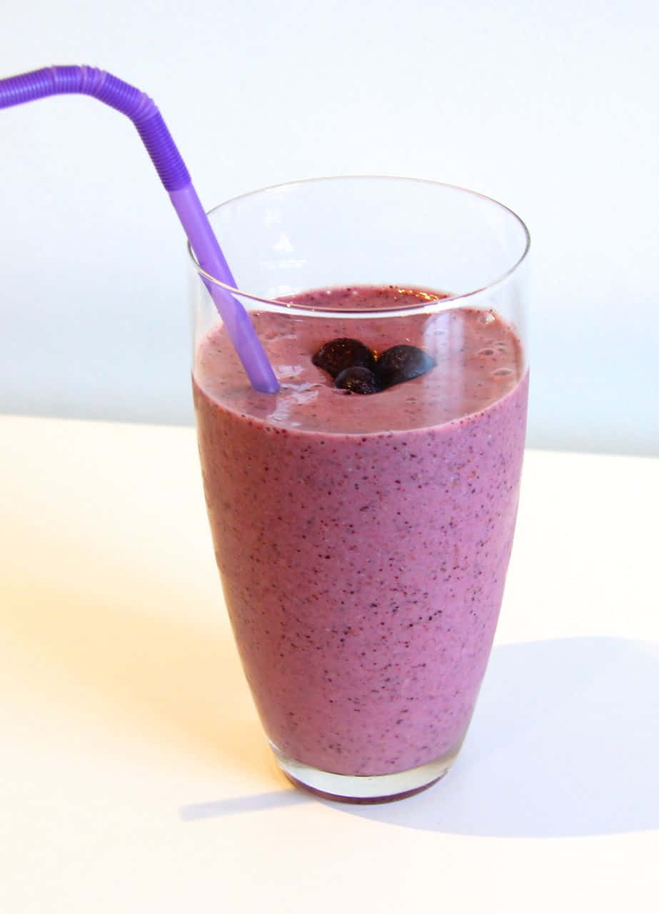 Blueberry Smoothie 桌布 壁紙 — 一杯充滿活力的紫色冰沙，盛載於透明玻璃杯中，上面綴以藍莓和紫色吸管，襯以亮白背景。