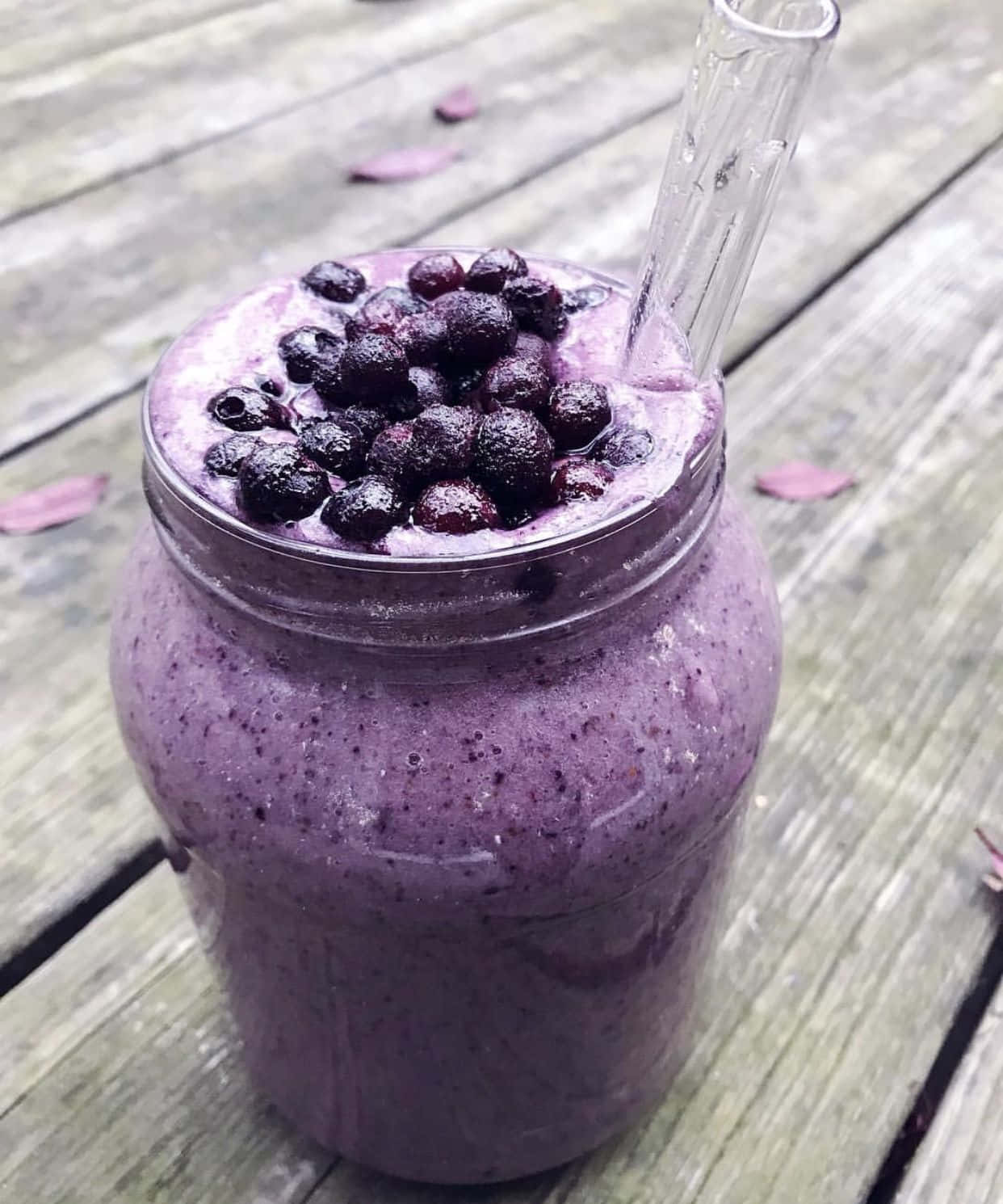 Blueberry Smoothie 桌布 壁紙 — 一杯充滿活力的紫色藍莓冰沙放在玻璃罐中，上面綴以新鮮藍莓和玻璃吸管，置於一張經風化的木桌上。