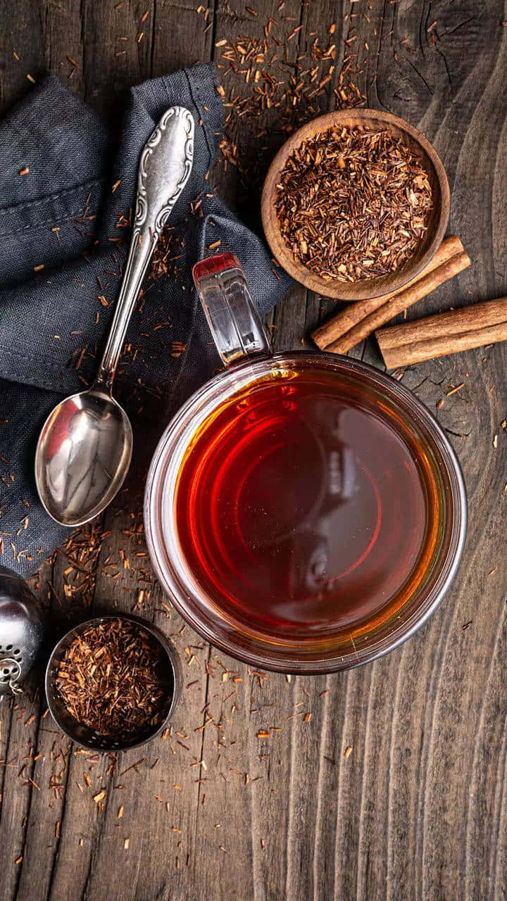 Morning Tea 桌布 壁紙 — 一杯冒煙的博士茶玻璃杯放在鄉村風木桌上，旁邊有肉桂棒和散裝茶葉。