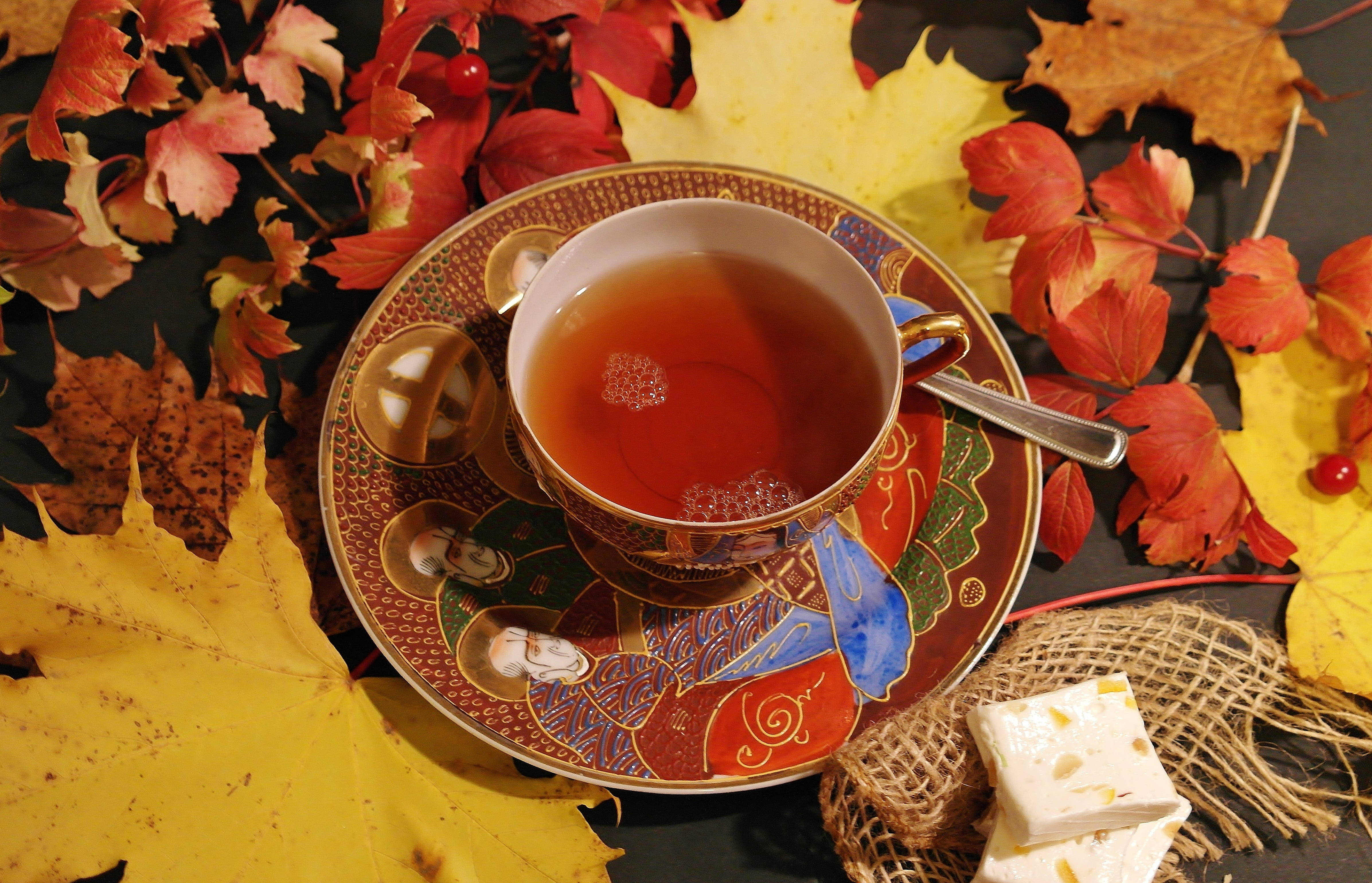 Cozy 桌布 壁紙 — 一杯冒煙的茶放在一個華麗的茶碟上，周圍環繞著鮮豔的秋葉和一塊方糖。