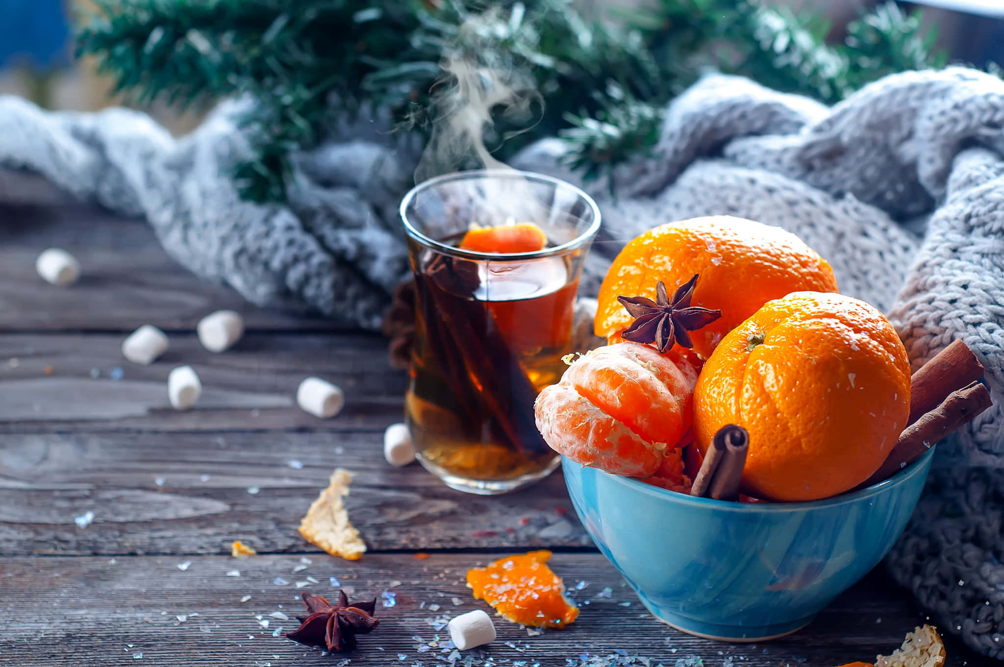 Mulled Wine 桌布 壁紙 — 一杯冒煙的香料茶，旁邊放著一碗柳橙和肉桂棒，置於鄉村風木桌上。
