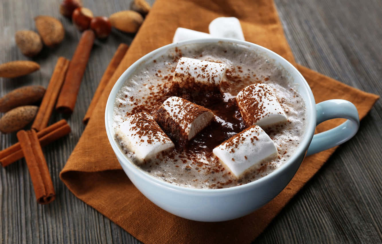 Milk And Coffee 桌布 壁紙 — 一杯冒著熱氣的熱巧克力，上面放著棉花糖和肉桂，放在一張散落著堅果和香料的木桌上。