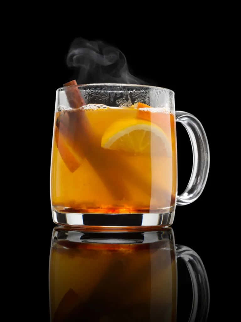 Winter Drinks 桌布 壁紙 — 一杯冒著蒸氣的玻璃杯裝香料蘋果酒，搭配肉桂棒和檸檬片，在黑色反光表面上溫暖地發光。