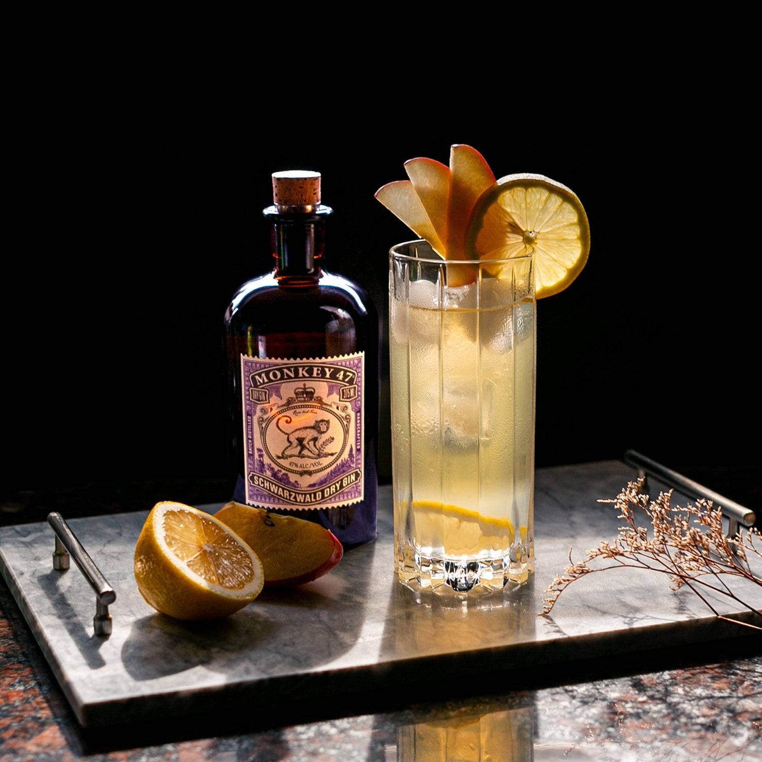 cocktail 桌布 壁紙 — 一杯冰凍雞尾酒配上柑橘片裝飾，放在大理石托盤上，旁邊有一瓶Monkey 47琴酒，背景為深色。