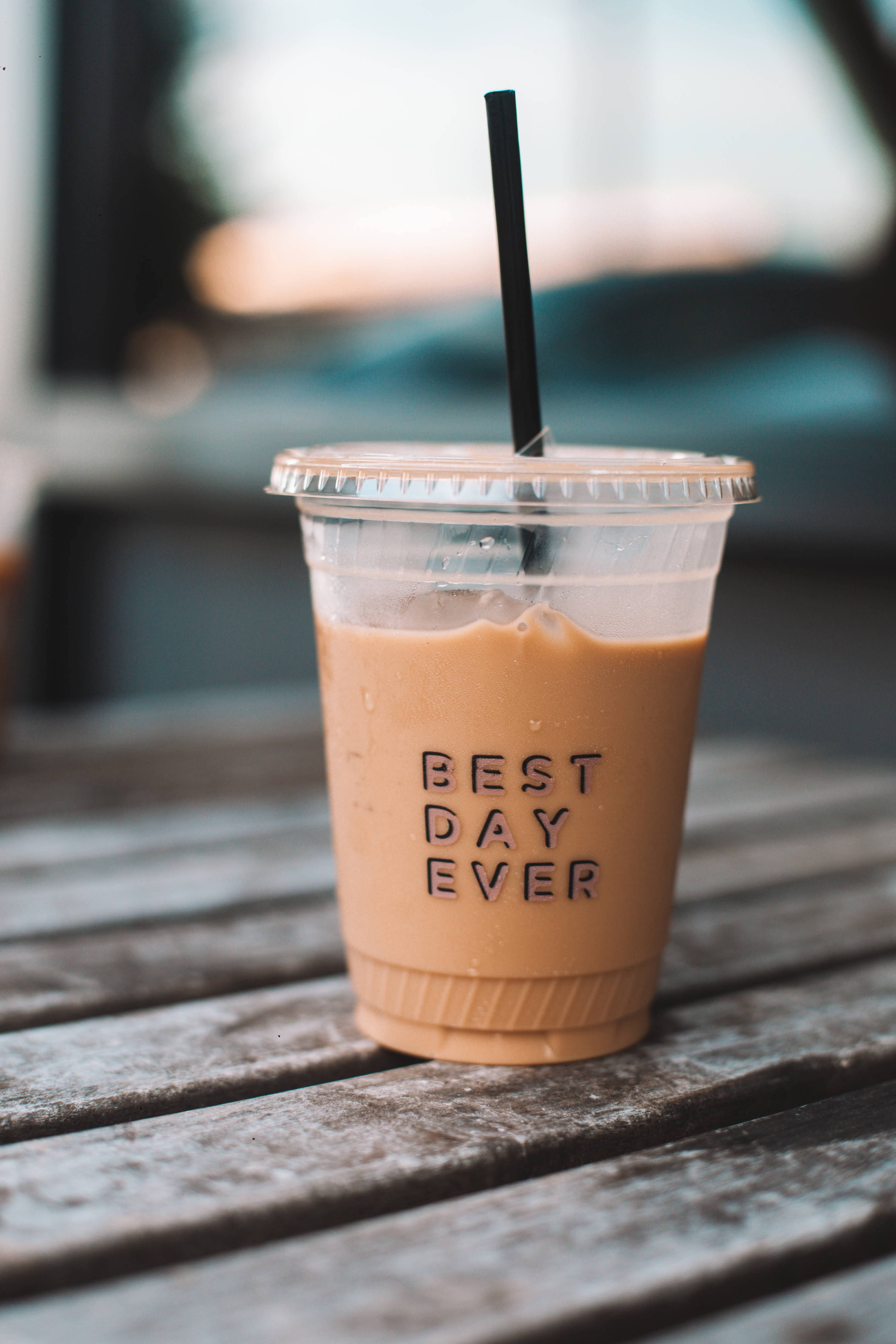 Positive 桌布 壁紙 — 一杯冰涼的冰咖啡在透明杯中，上面寫著「BEST DAY EVER」，放在室外一張風化的木桌上。
