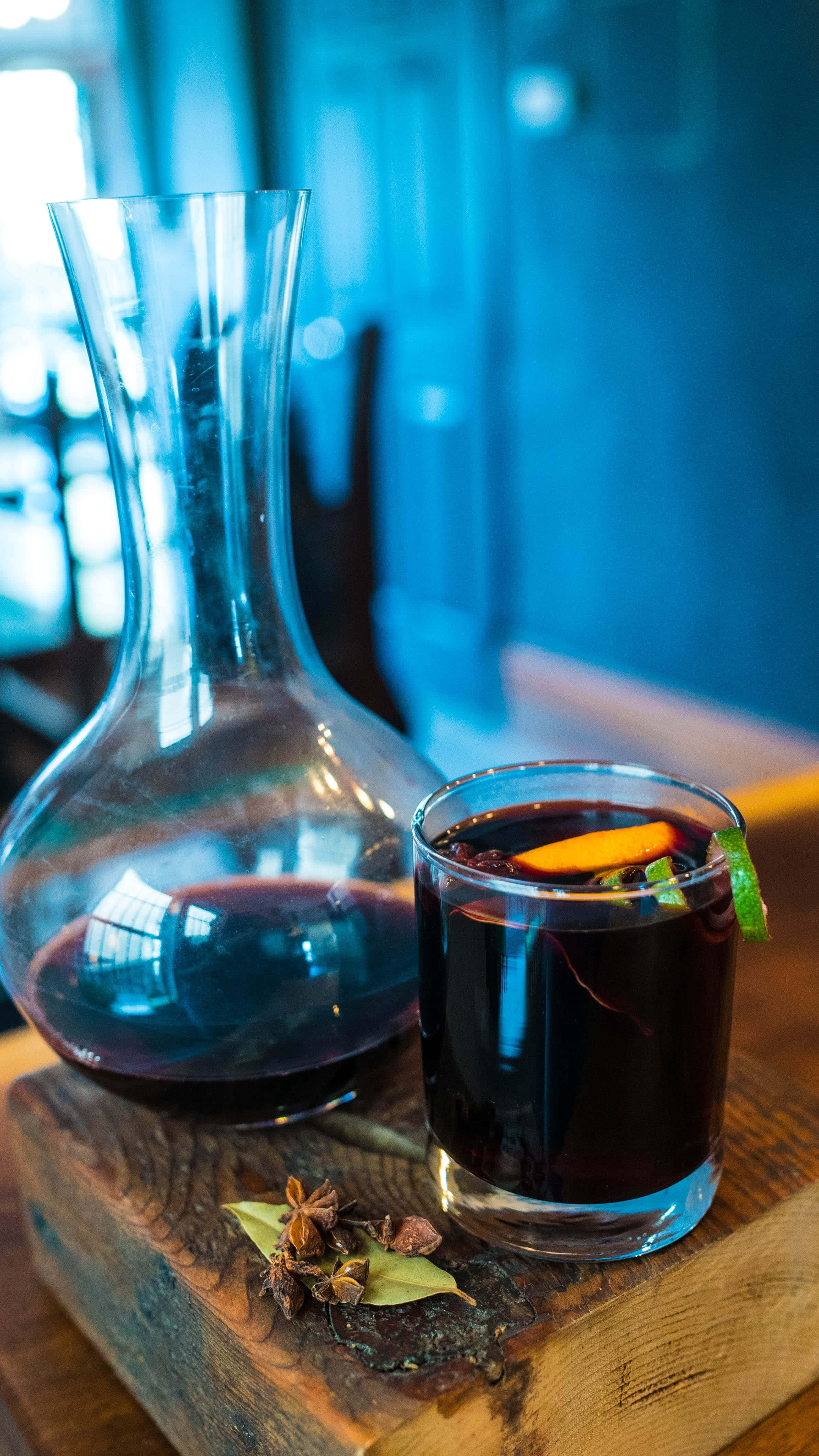 Mulled Wine 桌布 壁紙 — 一杯加了香料的熱紅酒，配上橙片和薄荷裝飾，放在一個鄉村風格的木板上，旁邊還有一個玻璃瓶。